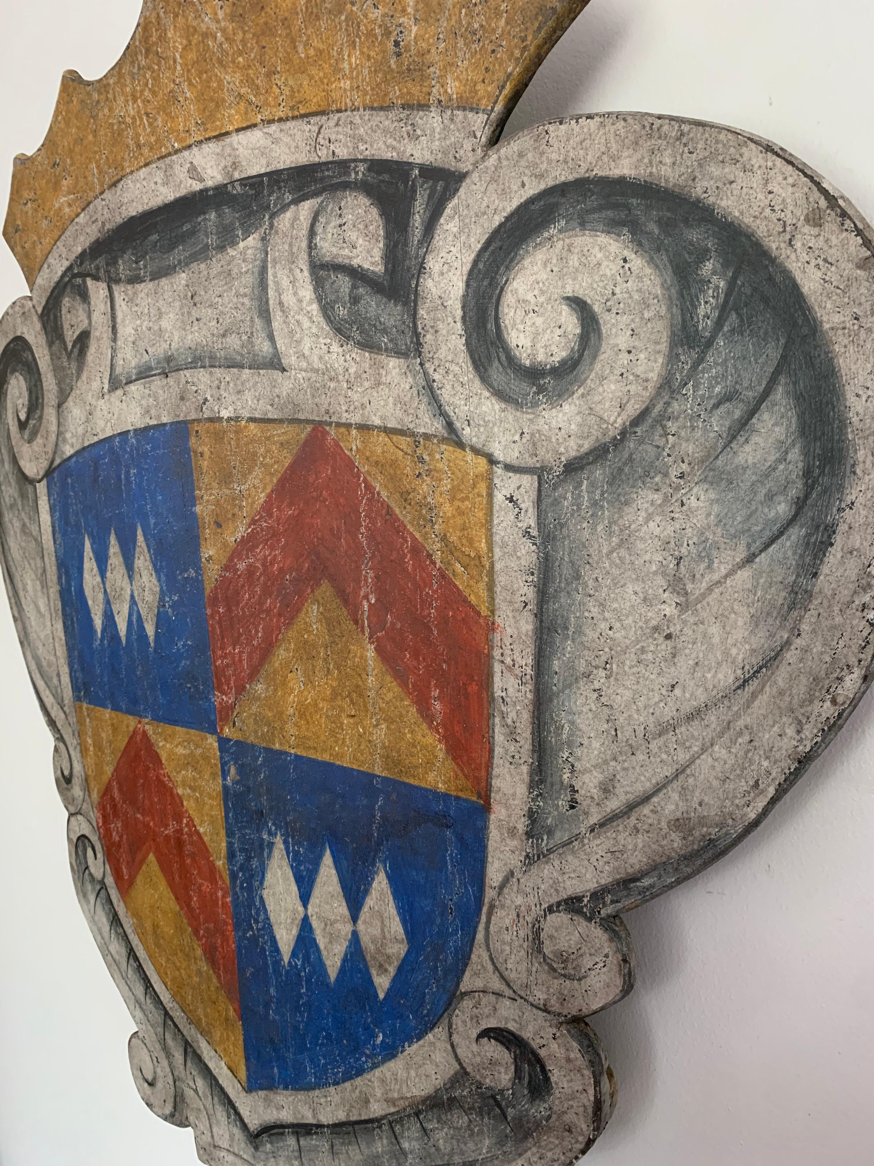 Decorate a games room or a study with this colorful painted curved plaque. Crafted in southern Italy, circa 1950, the painted wall sculpture features a center medallion decorated with a coat of arms with triple diamond and chevron motifs and a crown