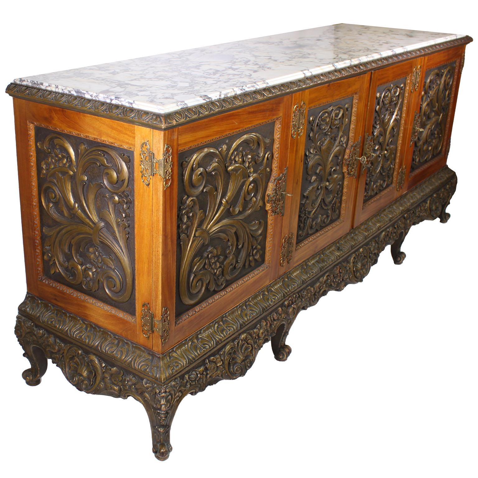 Un raffinato e grande server buffet italiano dei primi del Novecento, intagliato in legno dorato e montato in ottone dorato con piano in marmo. Il corpo rettangolare in legno di frutta con quattro porte anteriori ornate da scudi, volute e dettagli