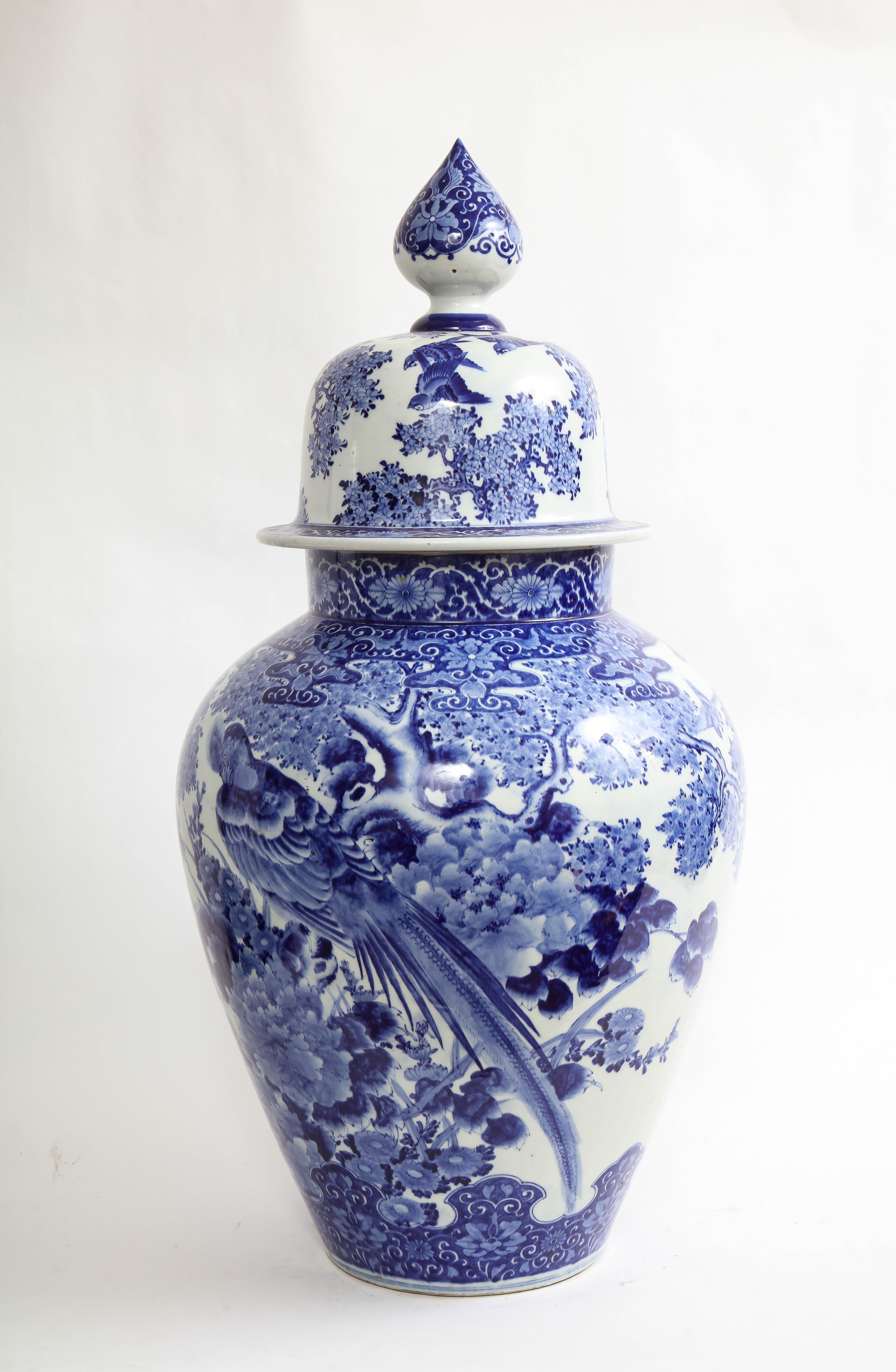 A Large Meiji Period Japanese Blue and White Covered vase with Pheasant and Flower Decoration. This piece is absolutely massive and beautifully decorated with hand-painted blue figures of pheasants on the body of the vase, as well as flowers, trees,
