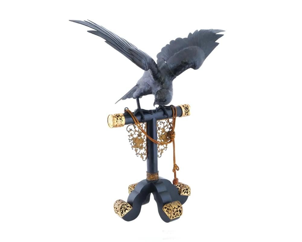An antique Japanese Meiji era bronze eagle on a perch. The eagle, with its head lowered and wings outspread, reflects the dynamic energy and alertness characteristic of these majestic birds. The detailing, likely down to the feathers and talons,