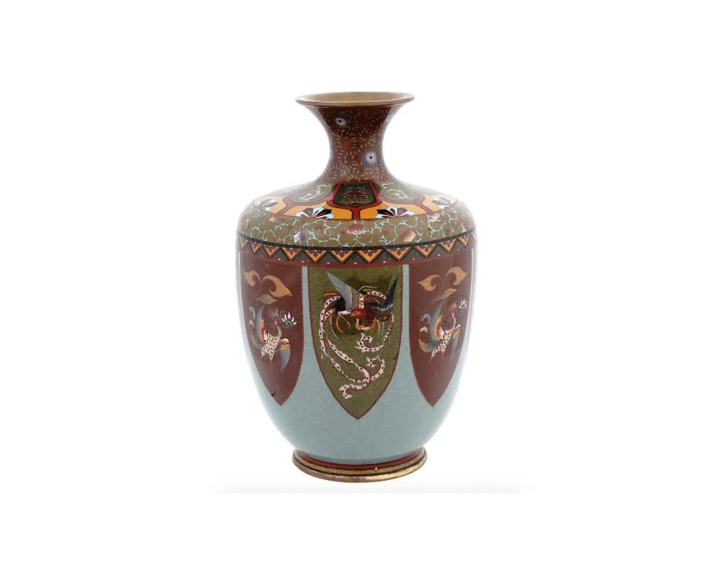 Vase en cloisonné japonais de belle qualité, au bord évasé, au col élancé et au corps en forme de balustre. La surface est émaillée de médaillons polychromes très détaillés représentant des oiseaux Phoenix très détaillés sur un fond bleu pâle et