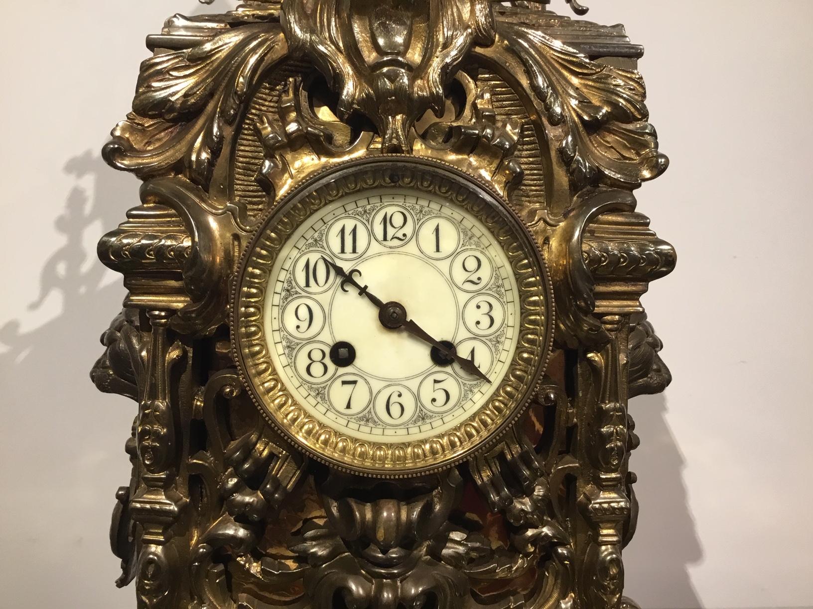 A large late 19th century French brass mantle clock. The elaborately cast brass case with a pagoda top, lions mask handles to the side and a pierced body. Standing on claw front feet and bracket rear feet. Having a porcelain enamelled dial and