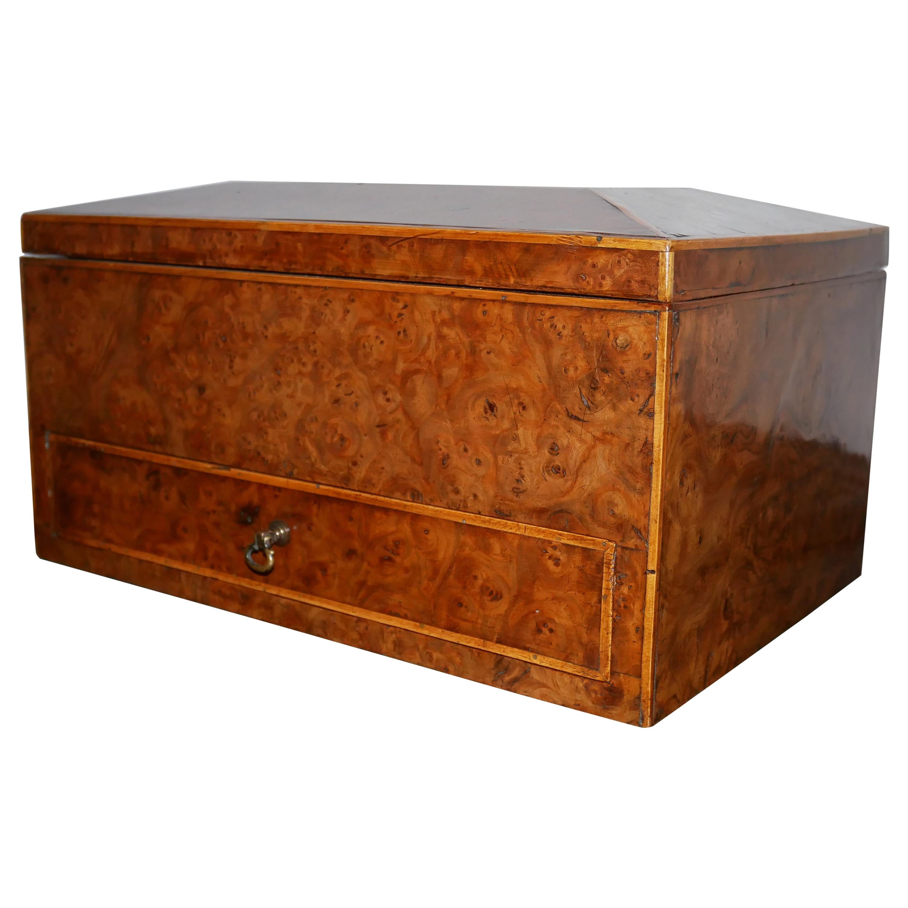 A large late Regency burr elm and boxwood strung work box, the sarcophagus shaped lift-off lid enclosing a void with removable borders, the drawer with a compartmentalized interior.
