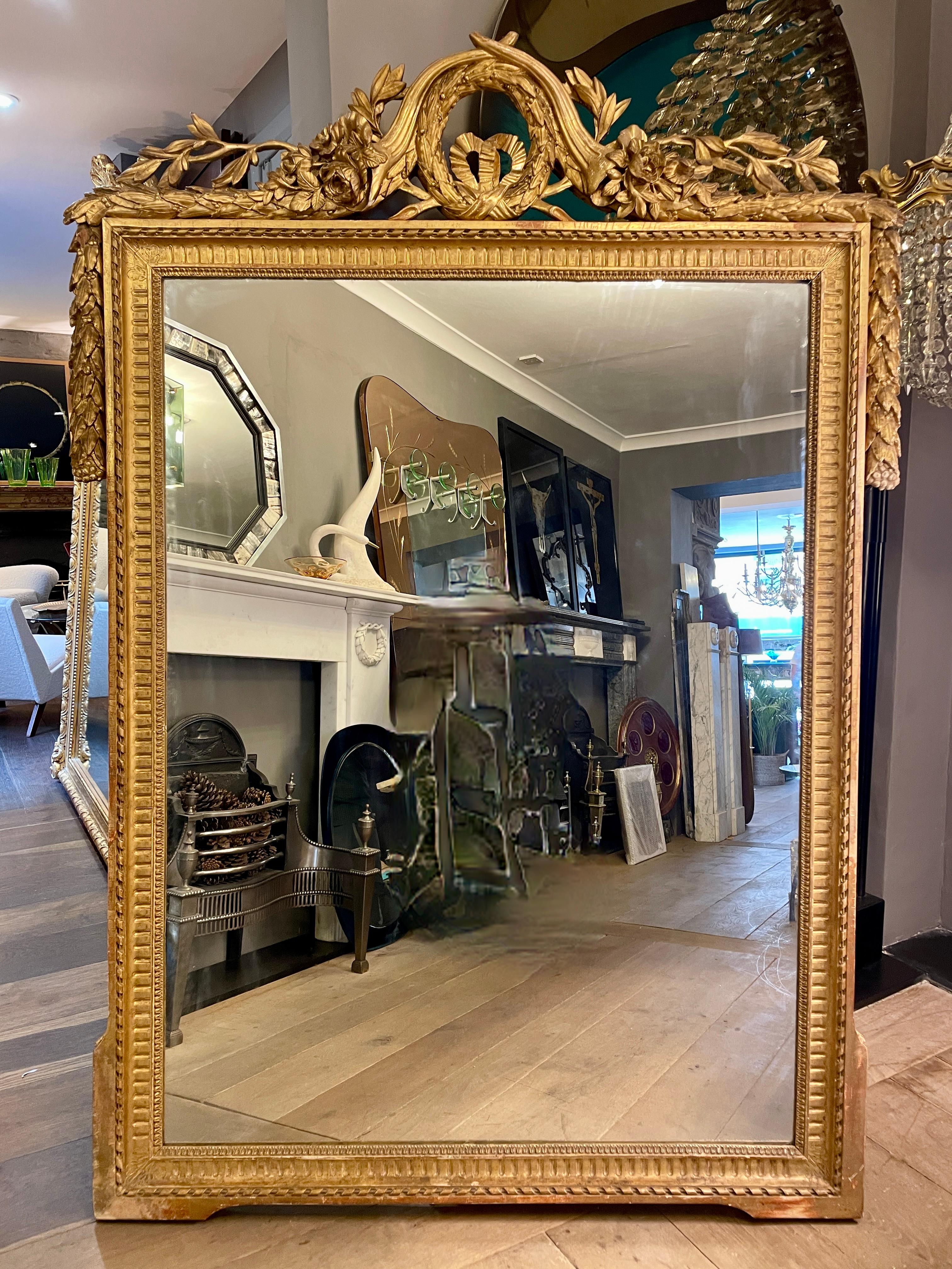A large and impressive carved giltwood Louis XVI period mirror from the late 18th century. The inner frame profusely decorated with ropetwist, stop flutes and egg and dart. The outer edge of the frame beaded. The pediment an array of decoration, the