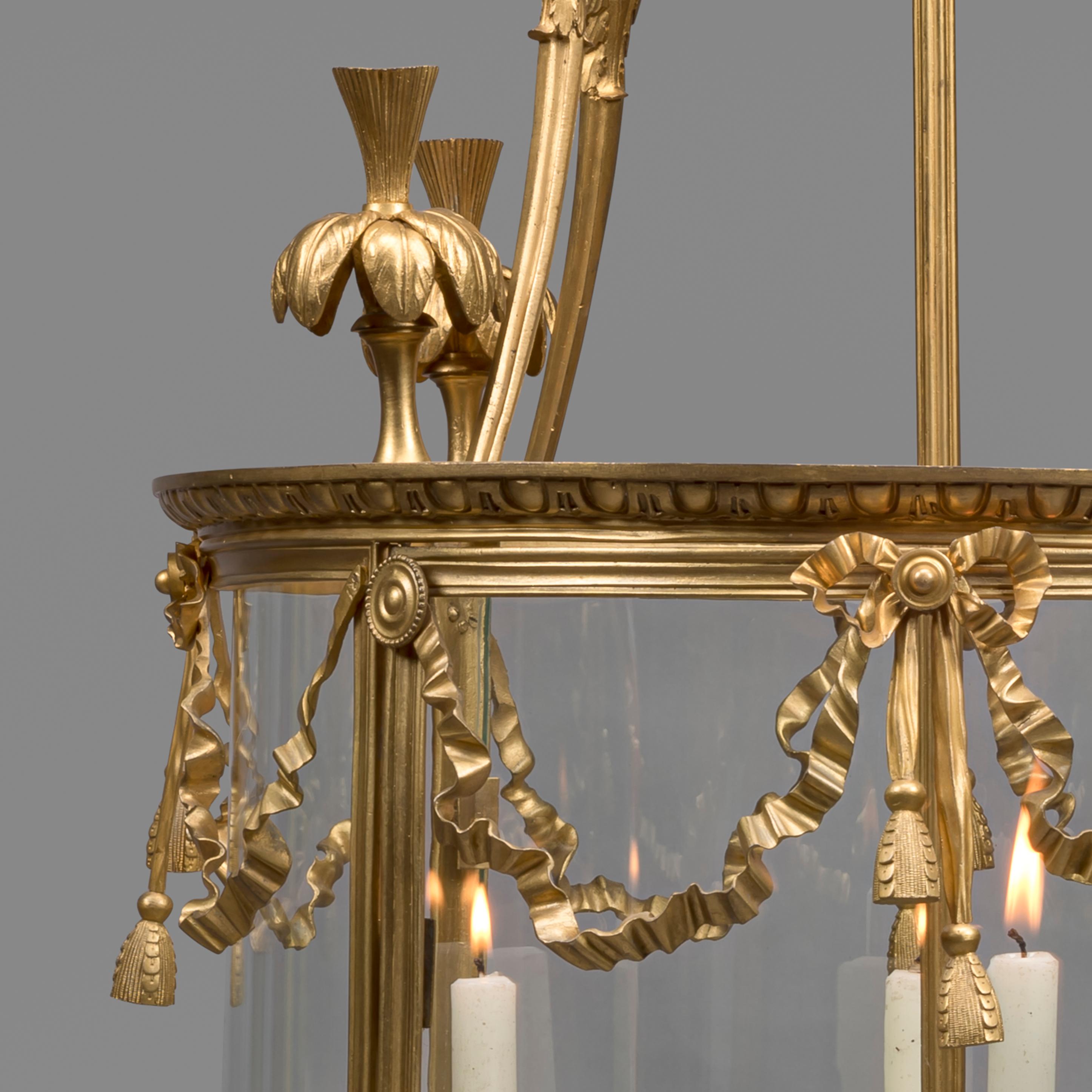 A large Louis XVI style gilt bronze cylindrical four-light lantern.

This large lantern is of cylindrical form with four ribbed uprights supporting a frame with beaded swags and ribbons and surmounted by ostrich-plume finials.

French, circa