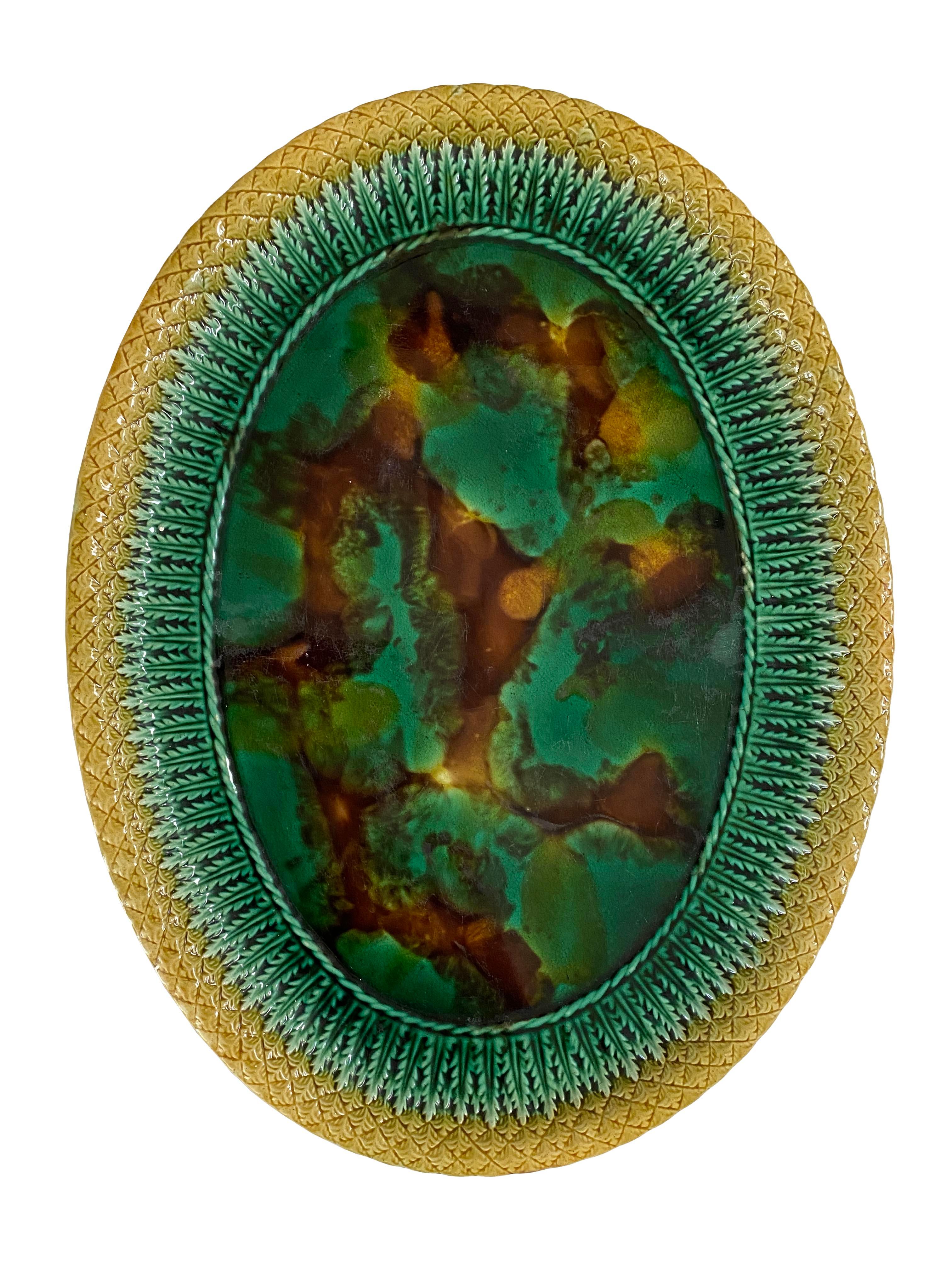 Ovale glasierte Servierplatte aus dem 19. Jahrhundert mit einem geformten Rand mit Korbgeflecht und Blattmuster. Eine gesprenkelte grüne, gelbe und braune Mitte. Ist unmarkiert. Aus der persönlichen Sammlung von Brooke Astor in ihrem Sommerhaus in