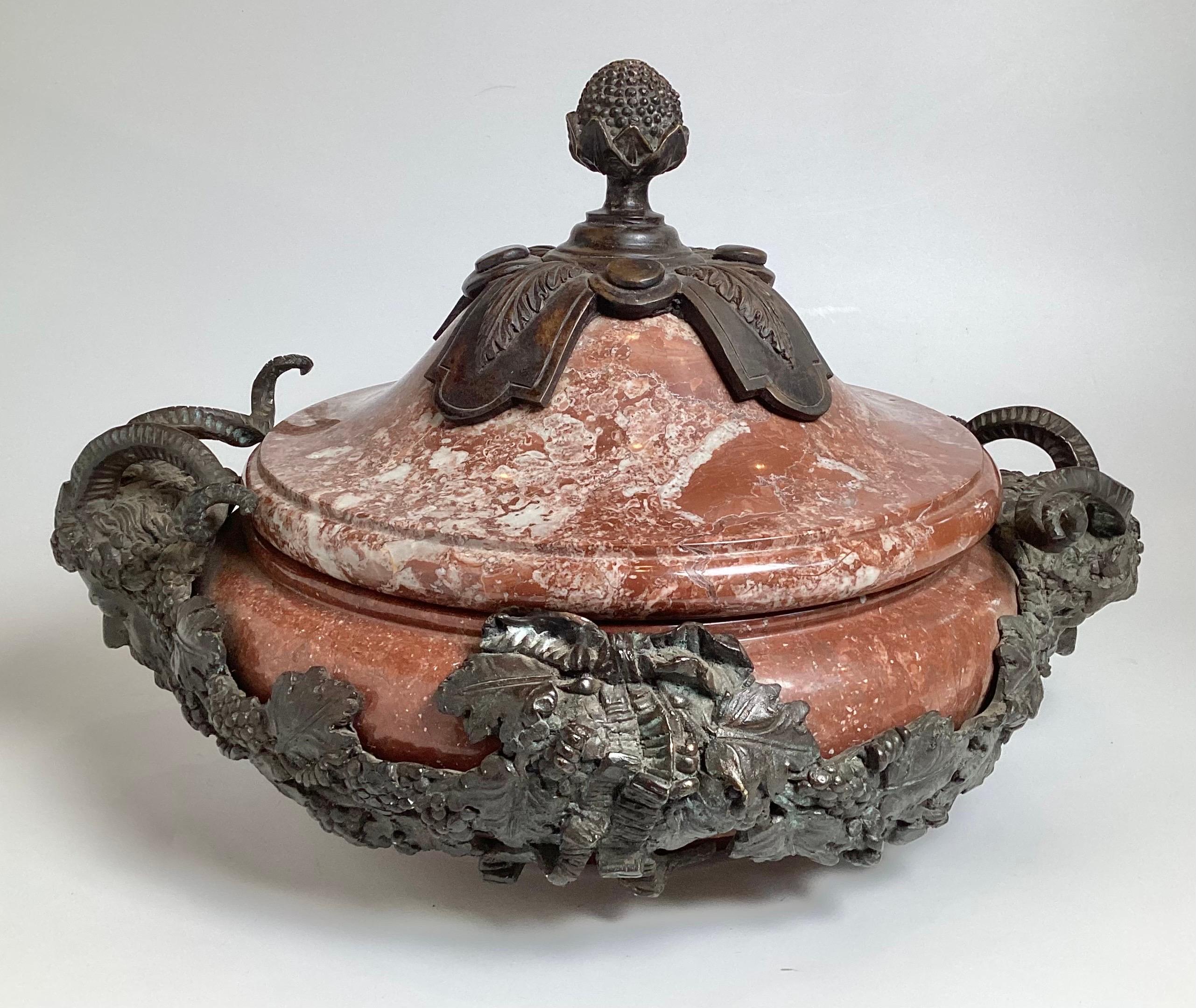 Una grande e pesante urna rotonda in marmo rosso e bronzo patinato.  Il vaso in marmo spesso con coperchio è montato con un motivo di uva e vite in bronzo fuso con maschere della figura mitologica di Pan.  Attribuito a Maitland Smith Fine del XX