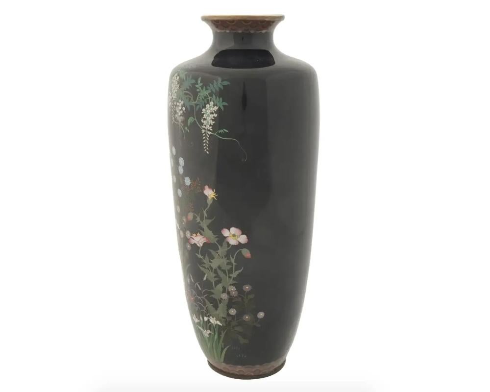 A Large Meiji Japanese Cloisonne Enamel Vases with Wisteria and Roosters In a Floral Landscape . Late Meiji period, before 1912. The vase has an elongated body and pronounced neck. The front side depicts roosters among wisteria flowers against the