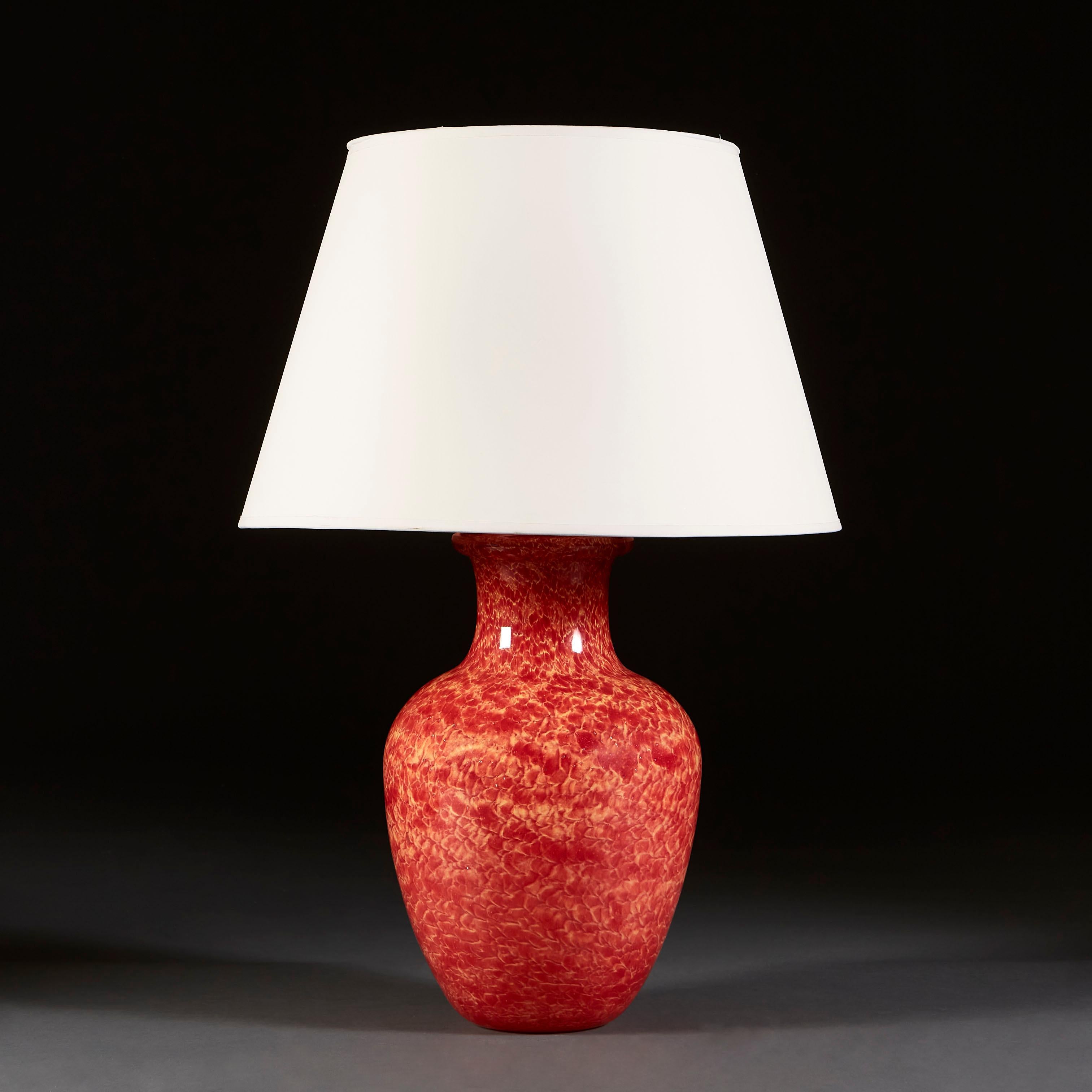 A mid-century French art glass vase as a lamp, with a fiery red glaze reminiscent of flowing lava that is broken into scale-like forms by areas of creamy orange.

Currently wired for the UK.

Please note: lampshade not included.