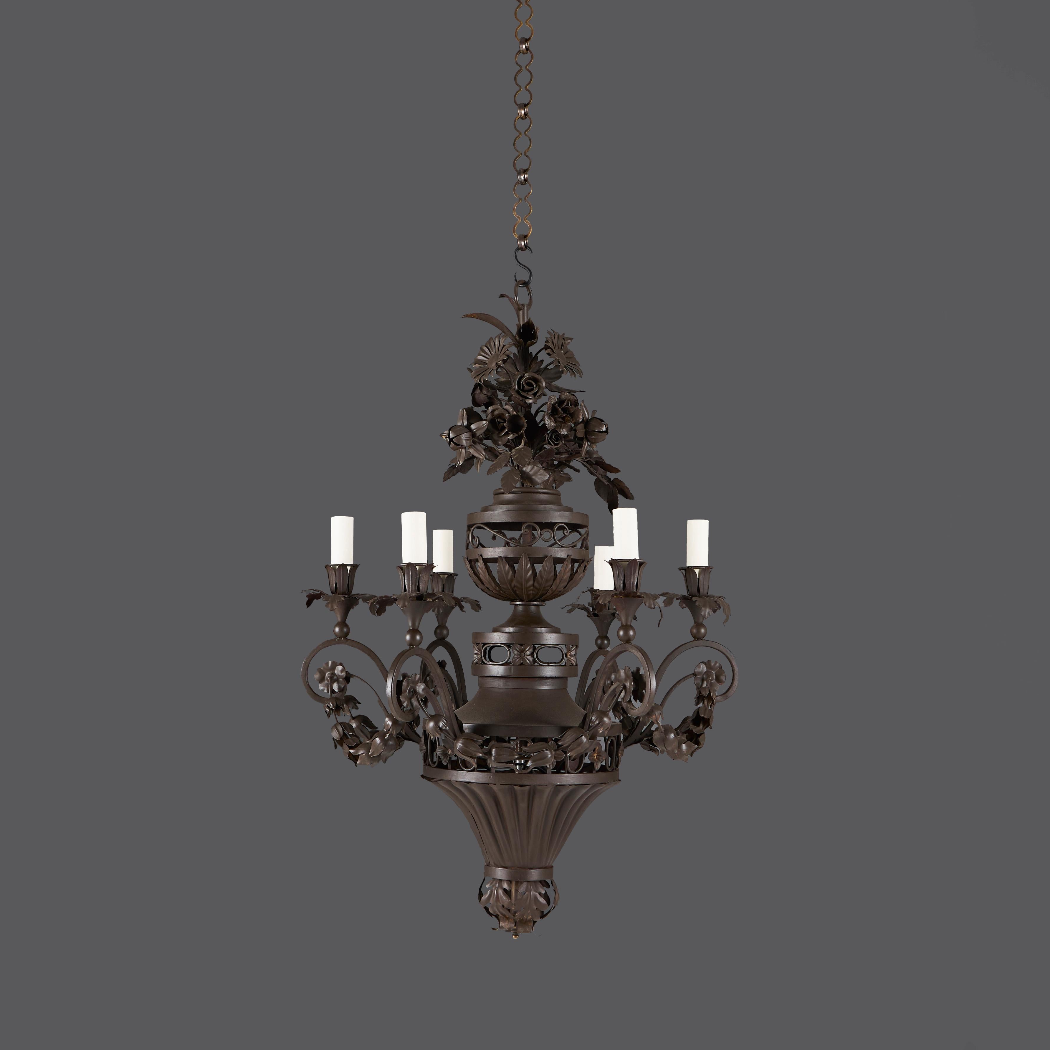 Grande lampadario neoclassico in tôleware e ferro battuto della fine del XIX secolo, con stelo centrale a forma di urna fiorita che sostiene sei bracci a spirale appesi a fasci di pula e con beccucci a forma di urna con attacchi per candele.

