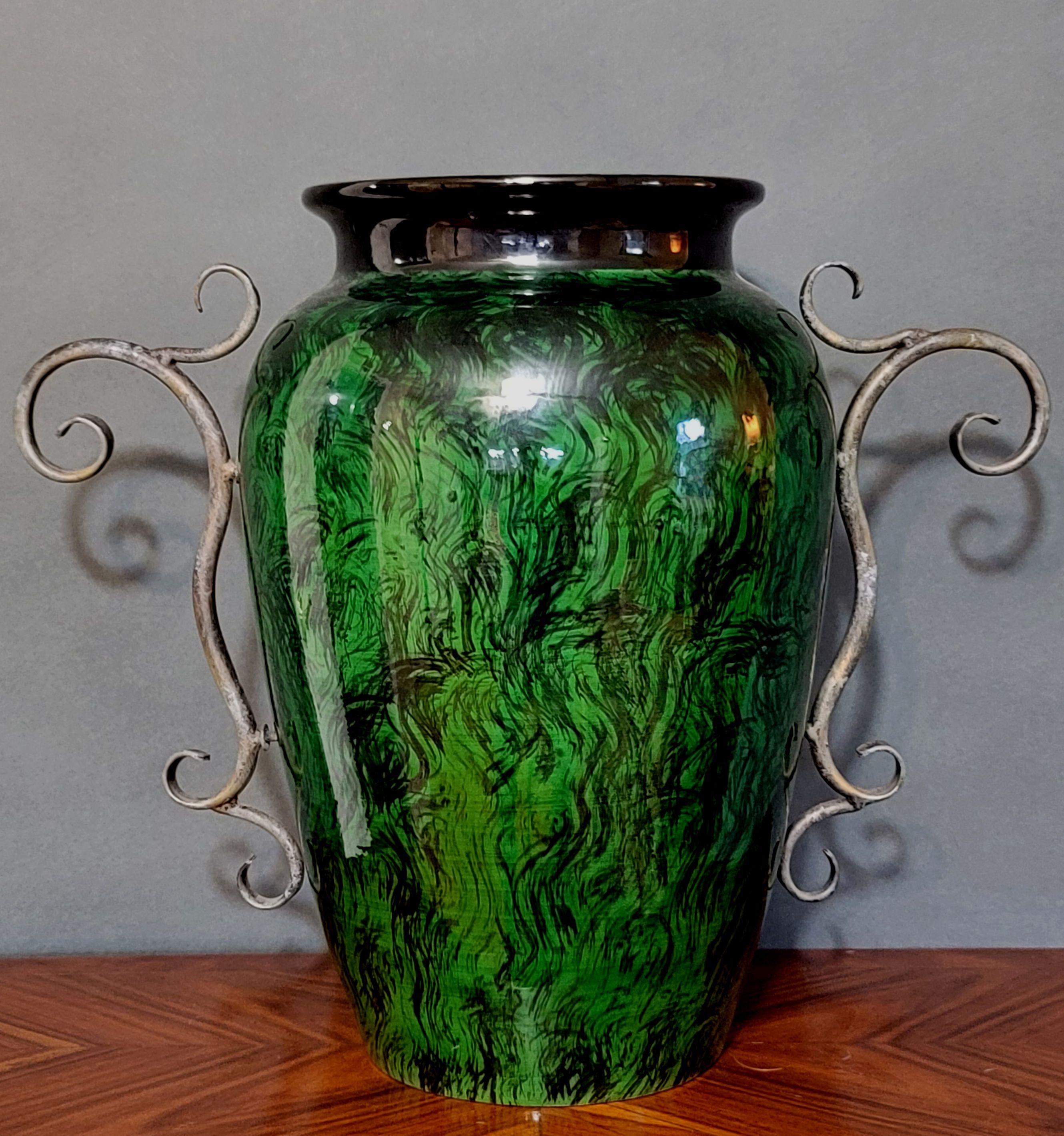 20th century
Large high choke vase with green and black glaze decorated with applied metal tendril handles.
    