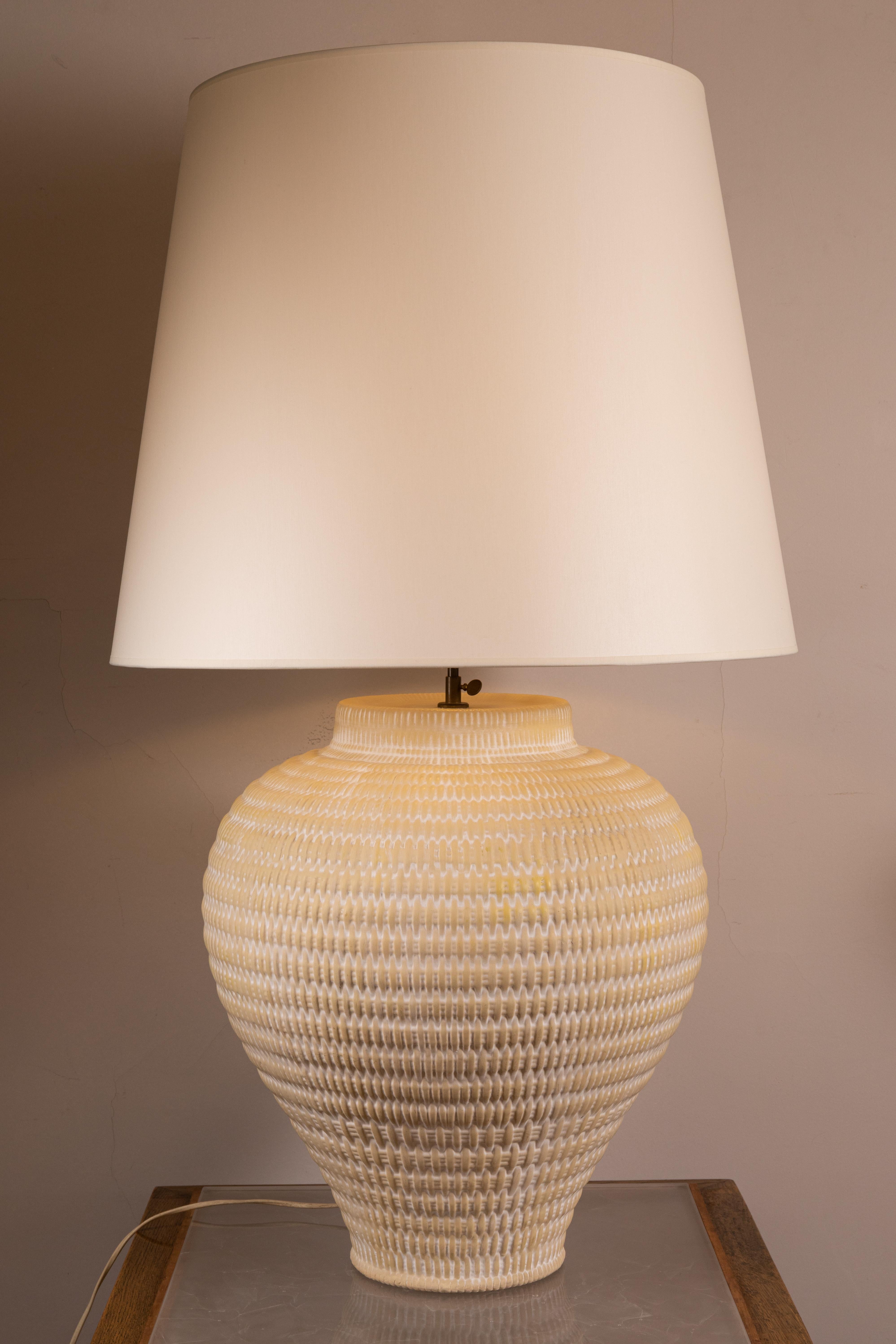 A large white ceramic table lamp 
Decorated with a wickerwork pattern. 
France, 1960

Dimensions : 
Total Height ( with shade) : 104 cm ( 40,94 inch ) 
Base height : 52 cm ( 20,47 inch ) 
Diameter : 44 cm ( 17,32 inch).