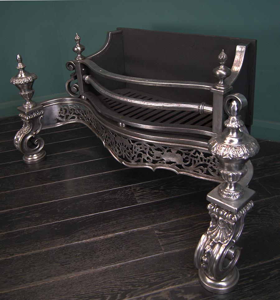A large ornate Regency manner wrought and cast-iron grate of serpentine form. The wide fire basket set on spheres and flanked by scrolls, all sits over an intricately engraved openwork fret with dragons. The grate is supported on foliated iron