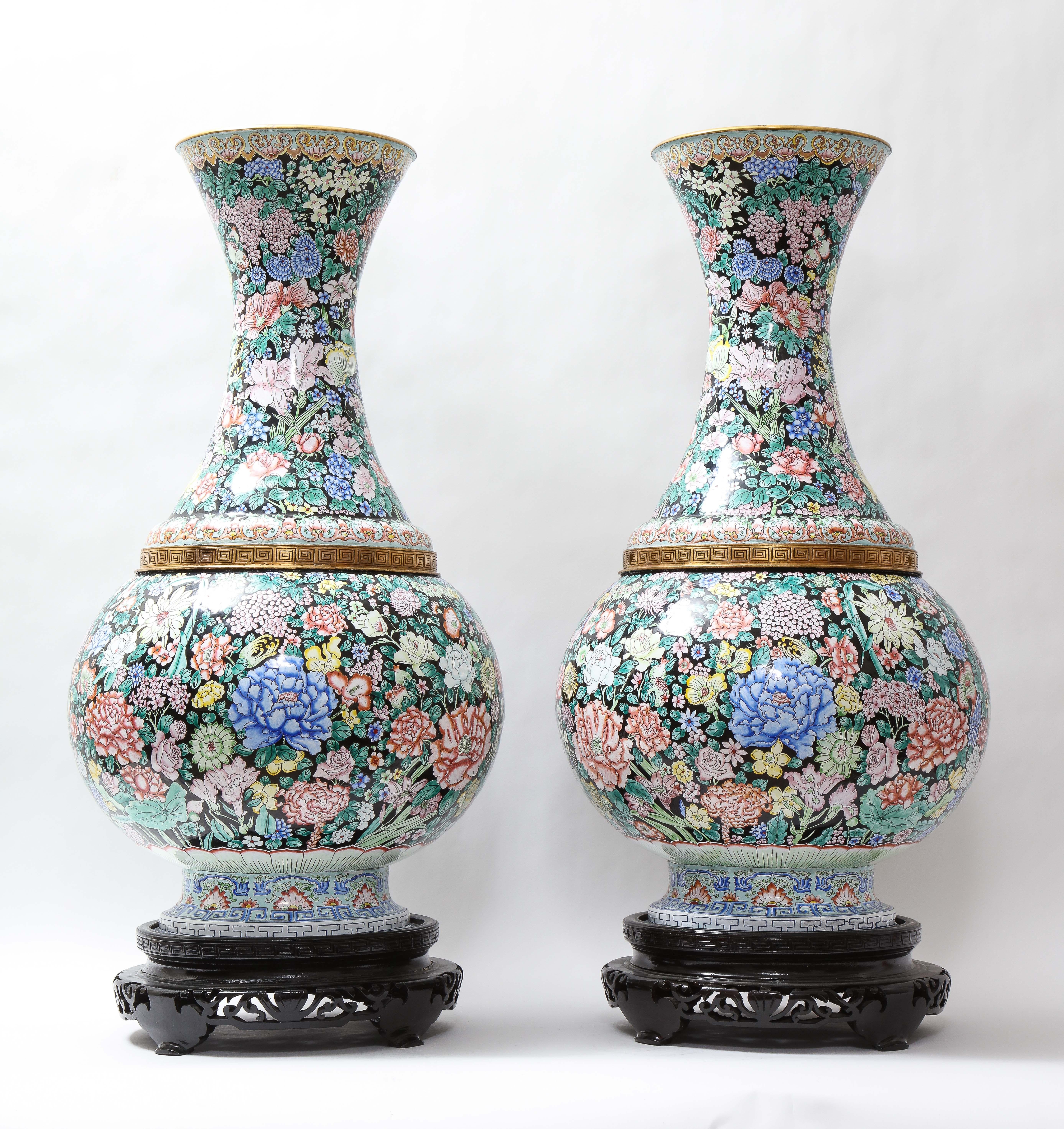 A pair of monumental Louis XVI style Chinese gilt bronze mounted Famille noir canton enamel vases hand-painted with flowers and fruits. Each is beautifully hand-crafted with canton enamel in multi-colored decoration. The vases are decorated in