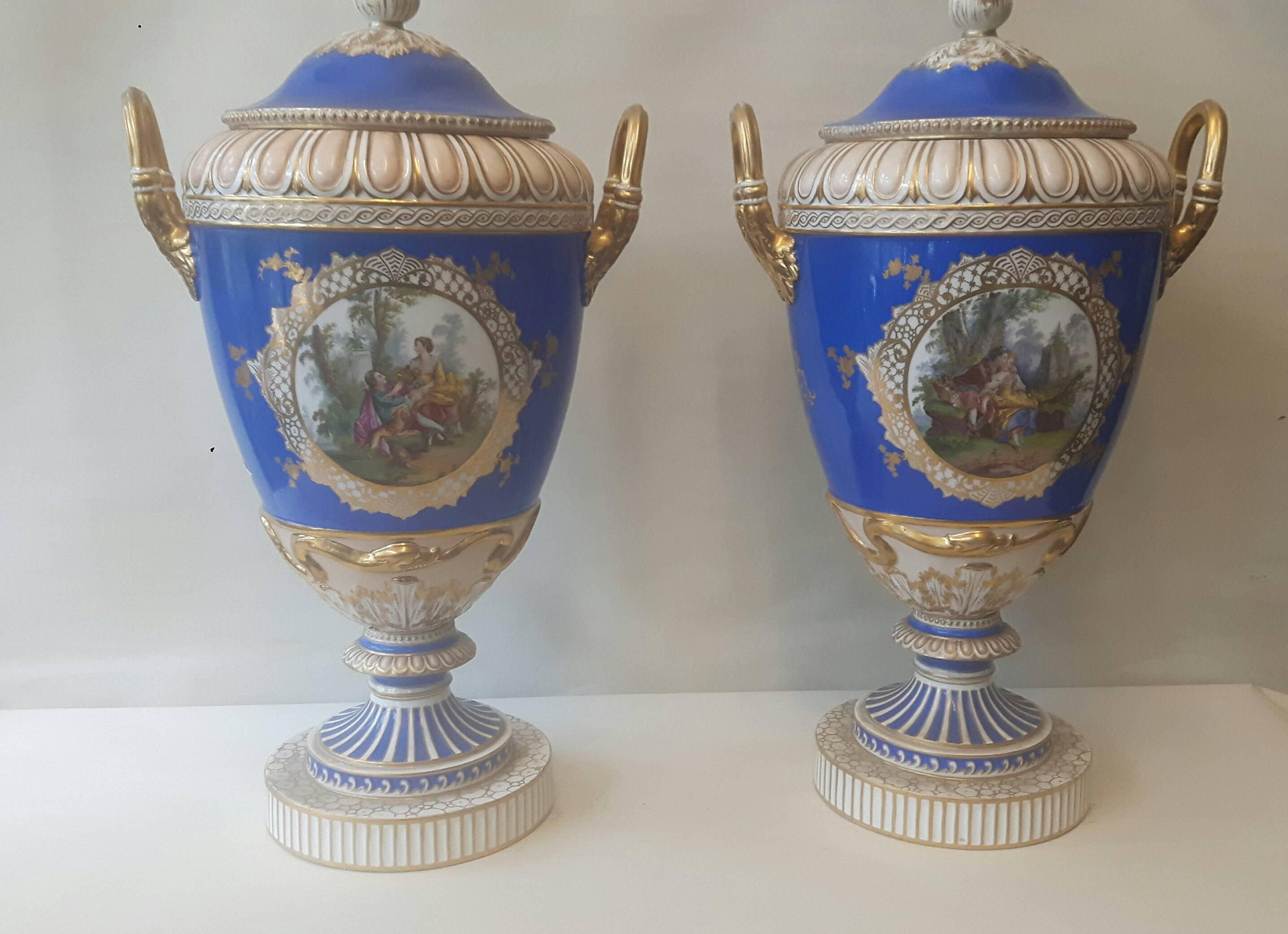 A large pair of Berlin porcelain urn-shaped vases and lids circa 1880, on a royal blue background, with hand-painted cartouches of pastoral scenes after Watteau.