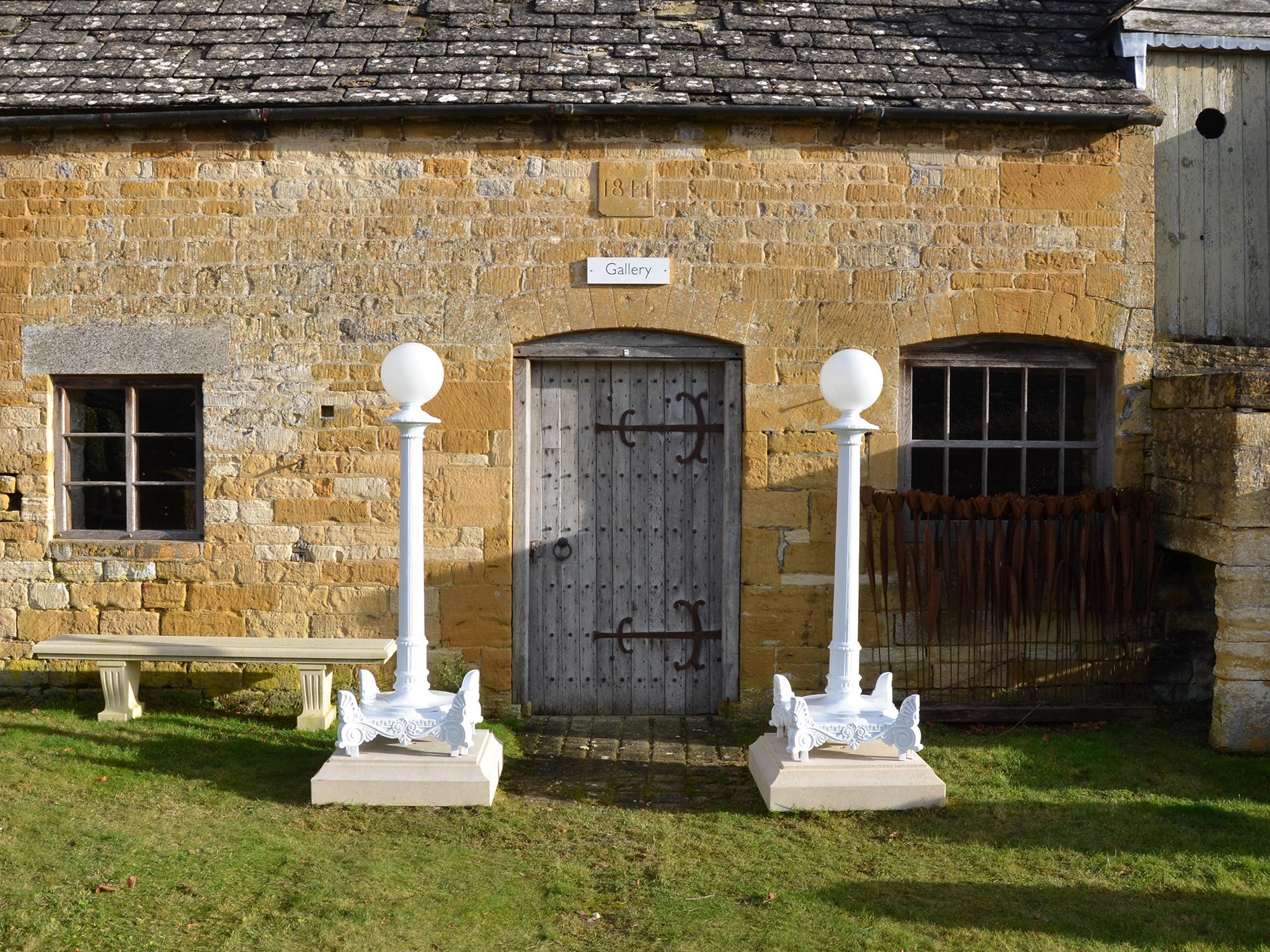 A large pair of 19th century cast iron lamp stands, circa 1840. In the neoclassic manner, the lamp shaft reeded rising to a flared cap with an egg and dart moulding, raised on square base with Anthemion ornament to each corner, with a central floral