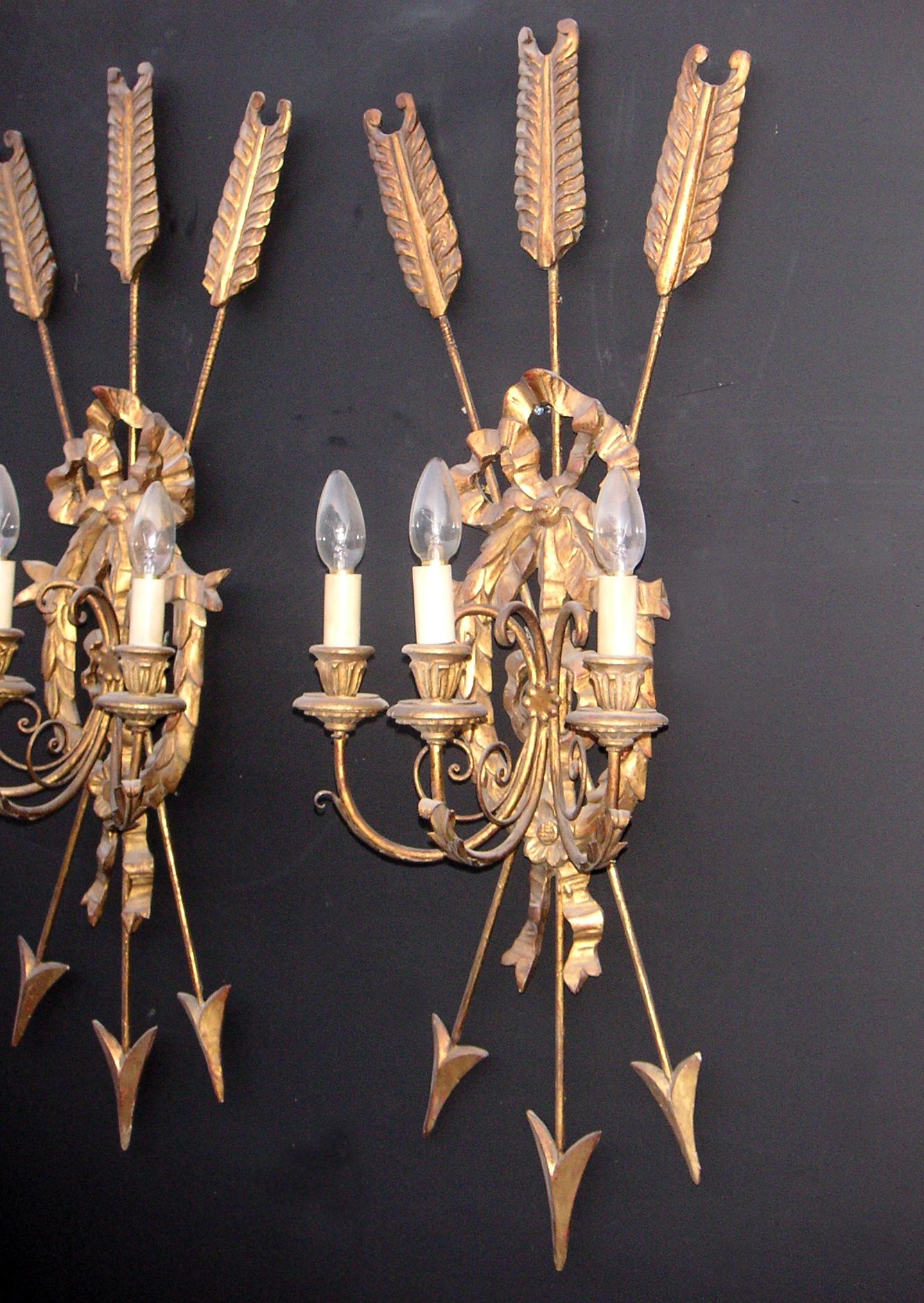 A large pair of 19th century giltwood wall lights with bow and arrow motif to centre and wreath tied by ribbons behind. 

Measures: Height: 35.75