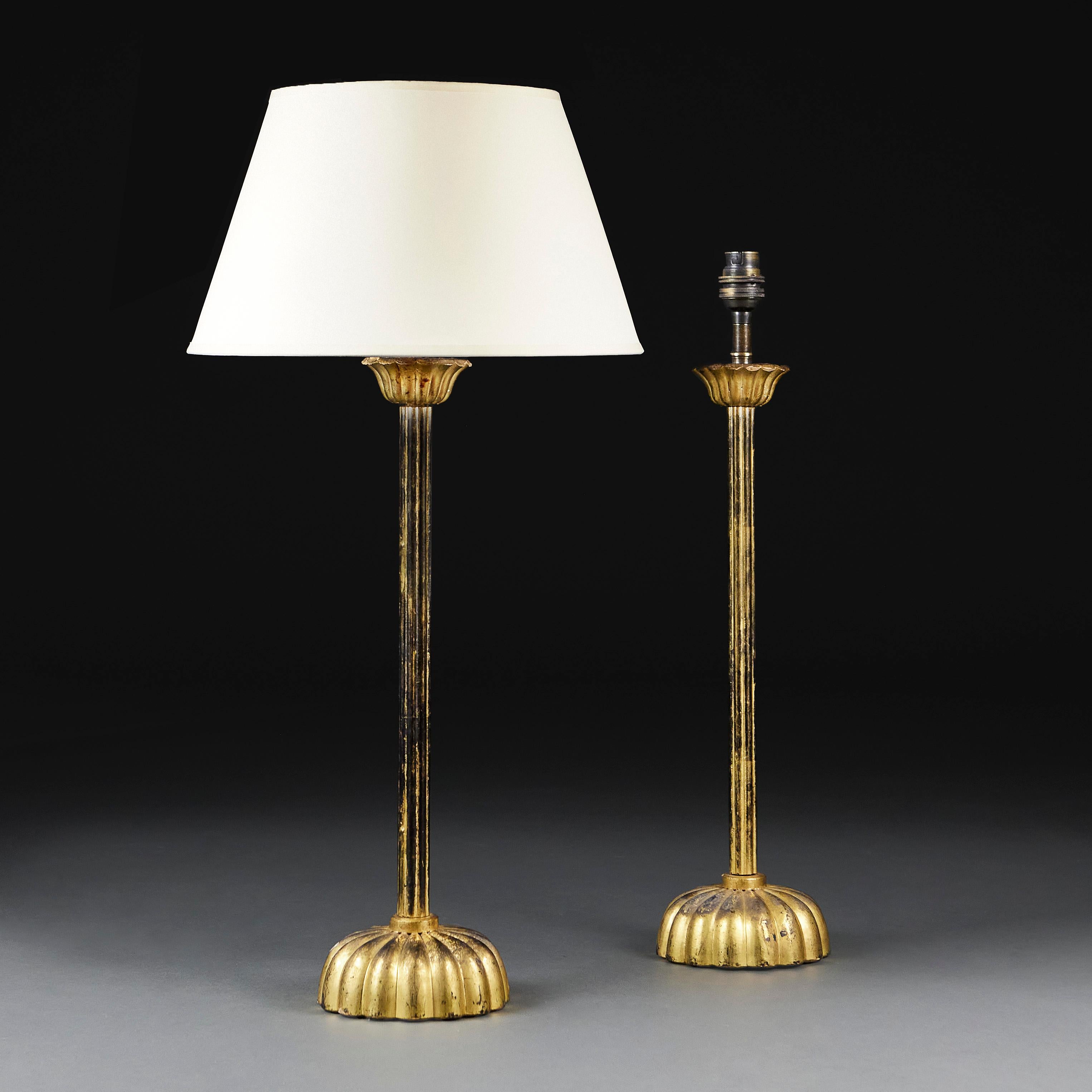 Japan, circa 1880
A fine pair of late nineteenth century gilded candlesticks with gadrooned central column, supported on a turned lotus form base, now as lamps. 

Height of column     58.00cm
Height with shade   83.00cm
Diameter of base   