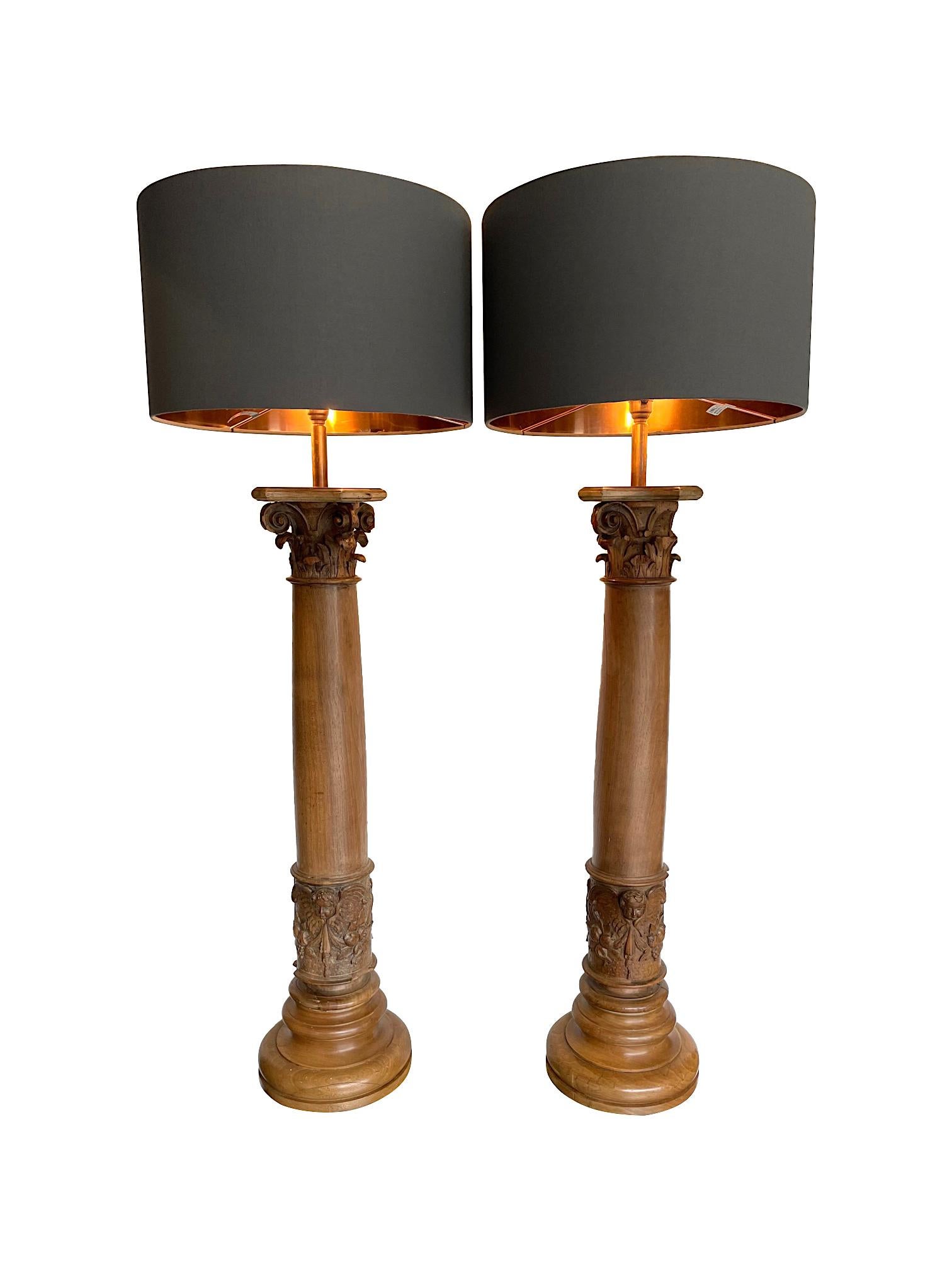 A large pair of 19th century oak Corinthian column lamps with central hand carved cherubs head and flower freize. The orignal 19th century columns have been converted later into lamps. Re wired with new brass fittings and antique gold cord flex.