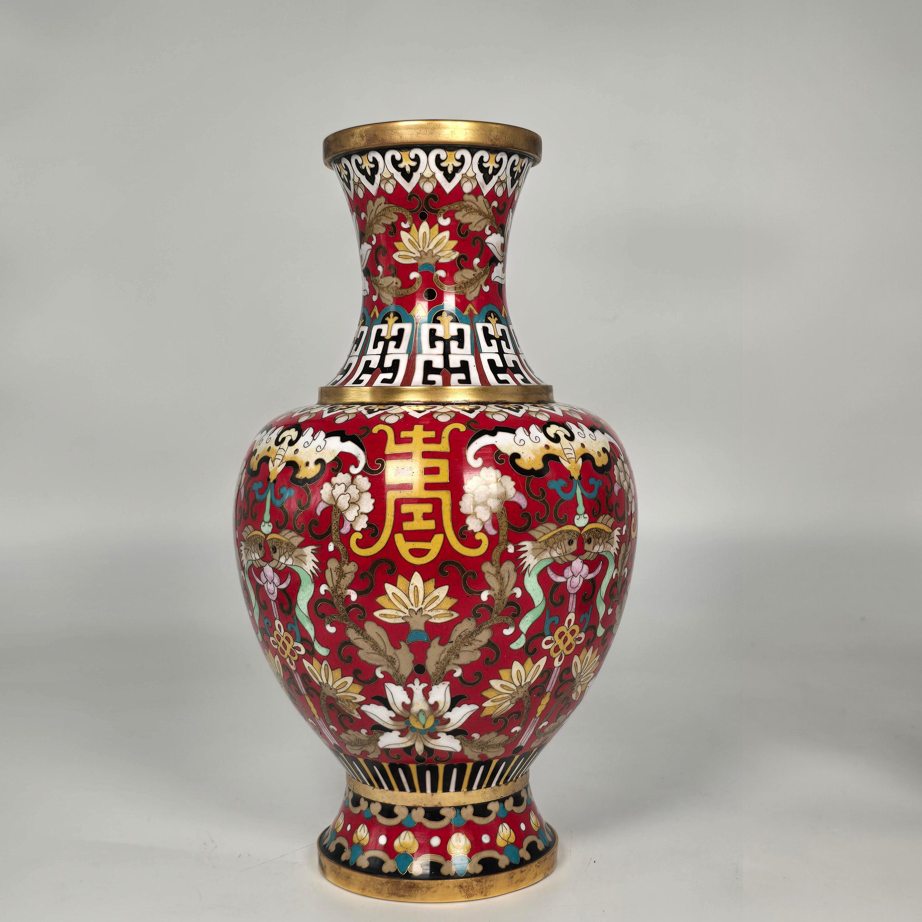This highly decorative pair of good-quality large-scale Chinese cloisonné enamel vases is most unusual. They have ornate decoration in rich, bright colours on a red background.

They are extensively decorated with numerous flowers, bats, fish, and