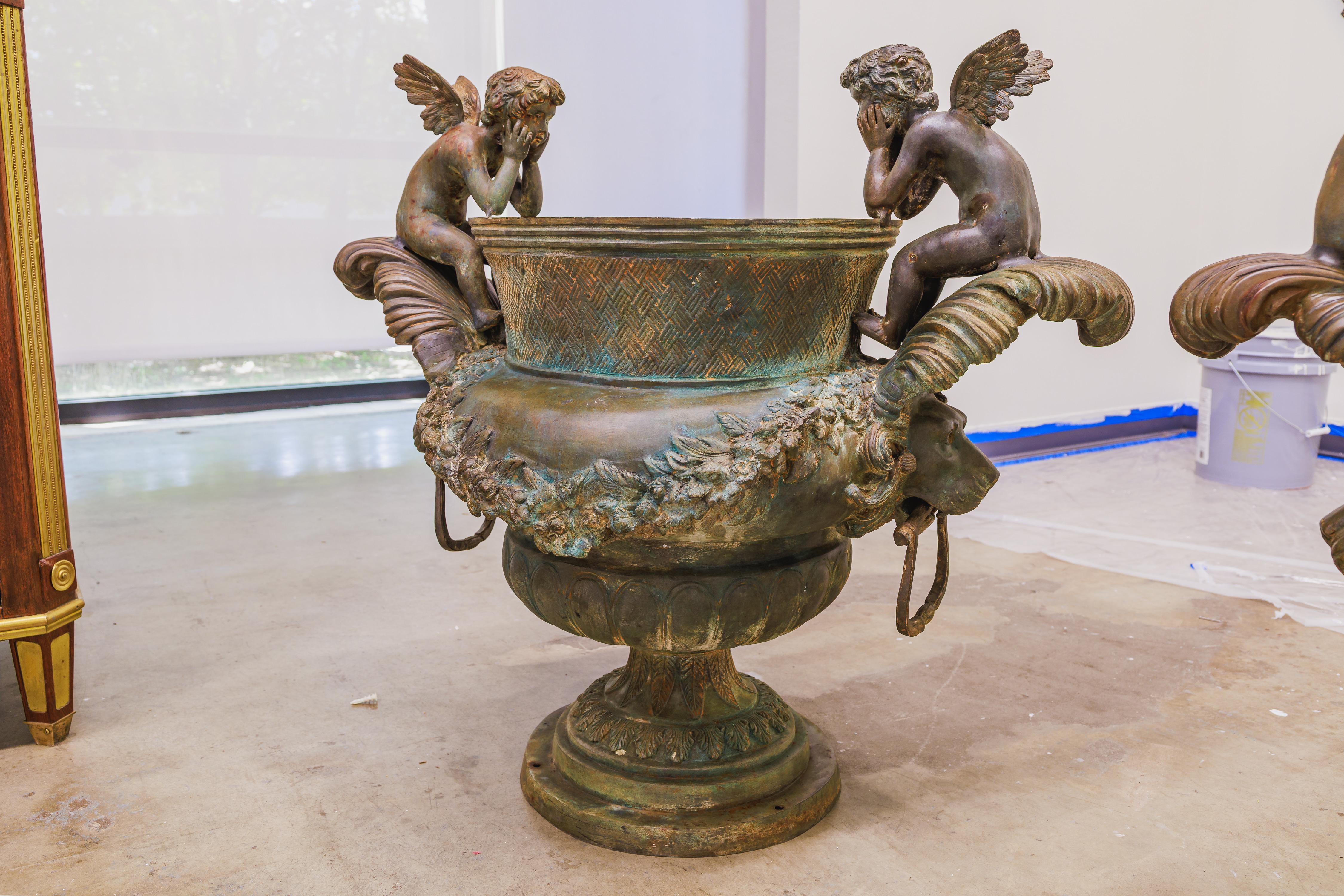 Une grande paire impressionnante d'urnes d'extérieur en bronze italien. Têtes de lion sur les côtés et chérubins ailés sur le dessus.