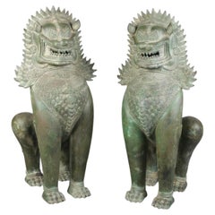Une grande paire de sculptures cambodgiennes en bronze modelées comme des lions de temple.
