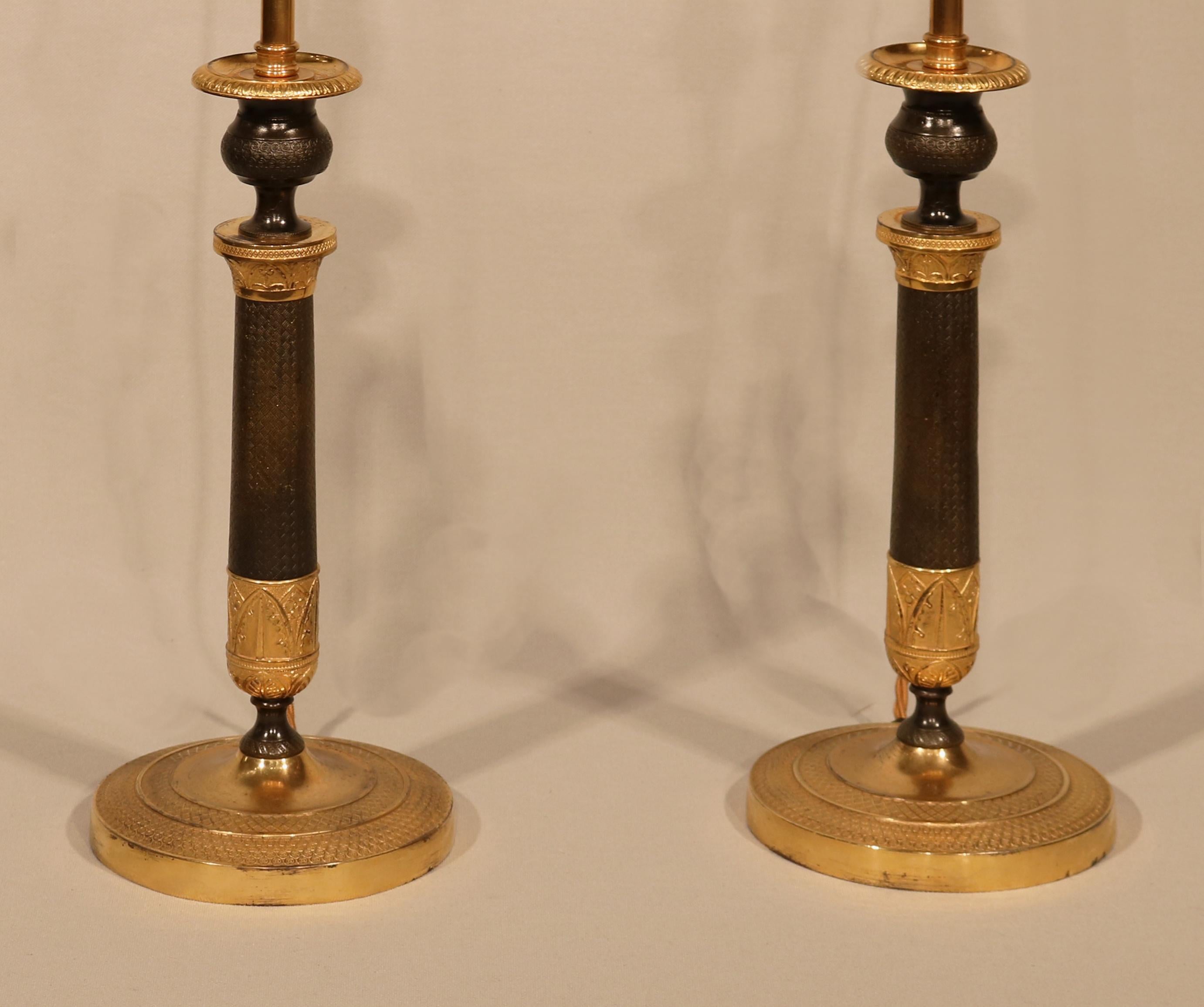 A large pair of early 19th century candlesticks having engine-turned urn-shaped nozzles above leaf and flower decorated engine-turned stems ending on similarly decorated circular bases.