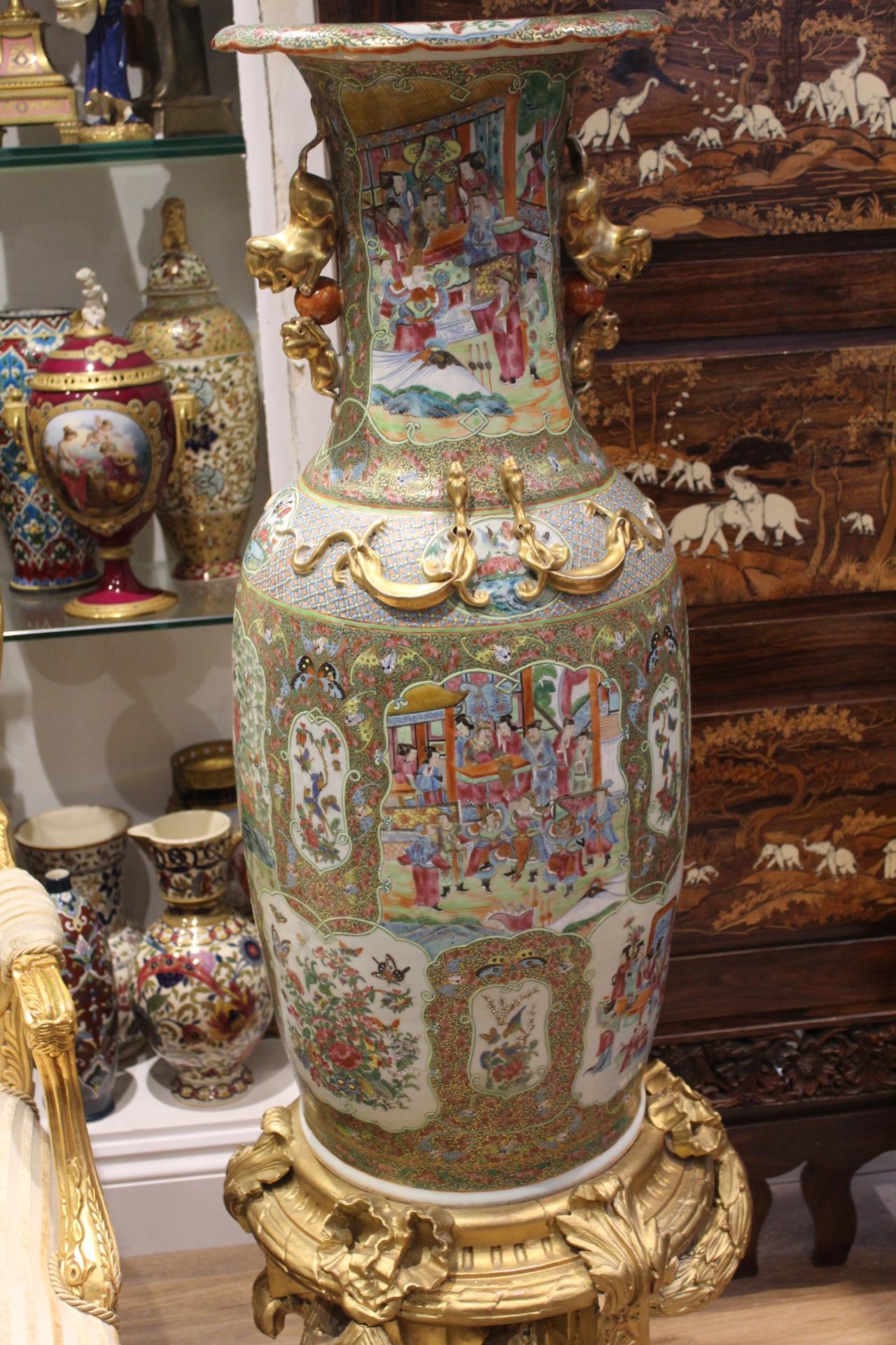A large pair of early 19th century Chinese canton famille rose porcelain vases with twin gilt kylin handles and applied gilt relief dragons, the body decorated with vignette panels depicting court scenes together with birds and butterfly's amongst