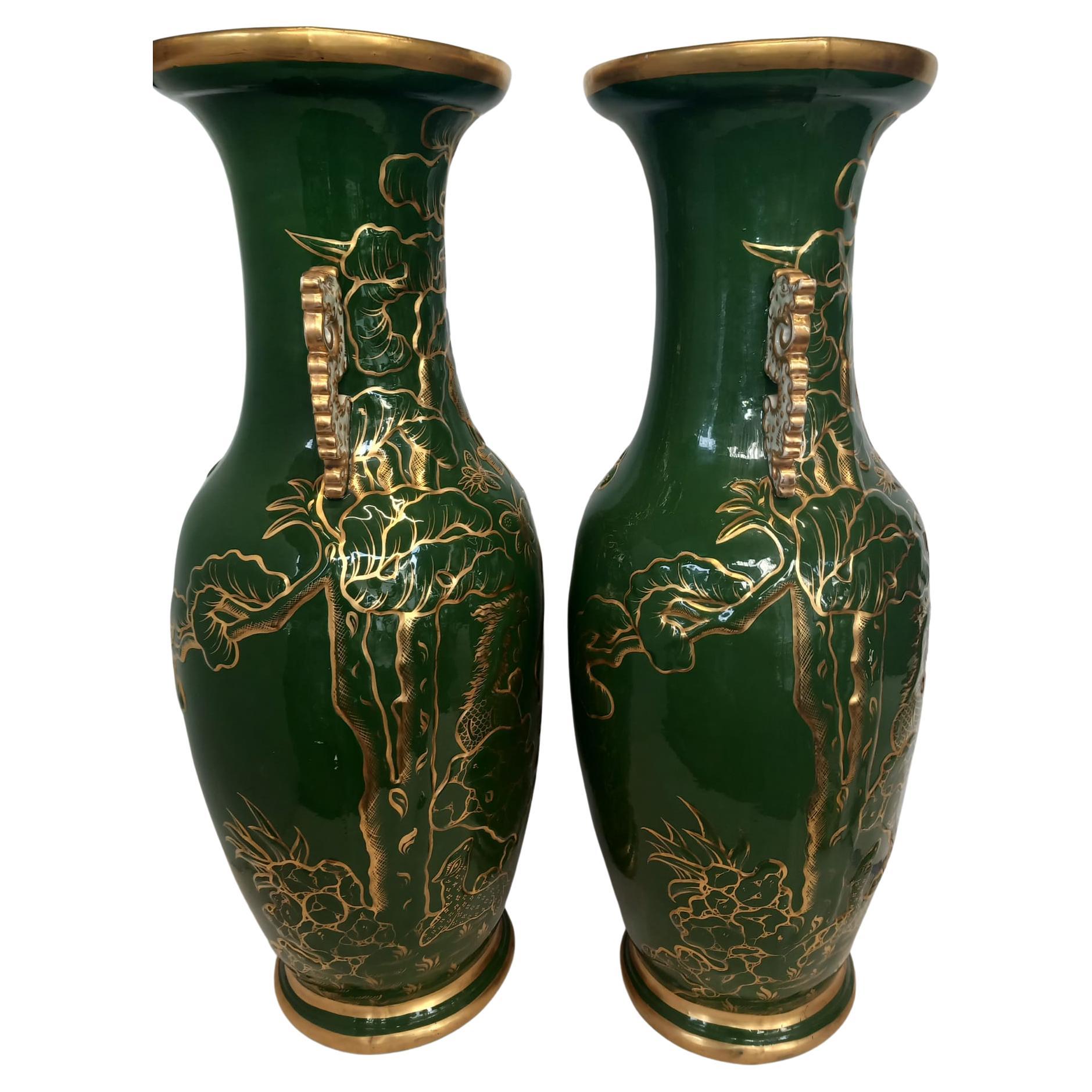 A pair of antique English ironstone vases dating from the mid nineteenth century. 
Hand decorated with gilded butterflies and moths , birds and foliage on a dark olive green background , with white and gold Chinoiserie style handles . 
These large
