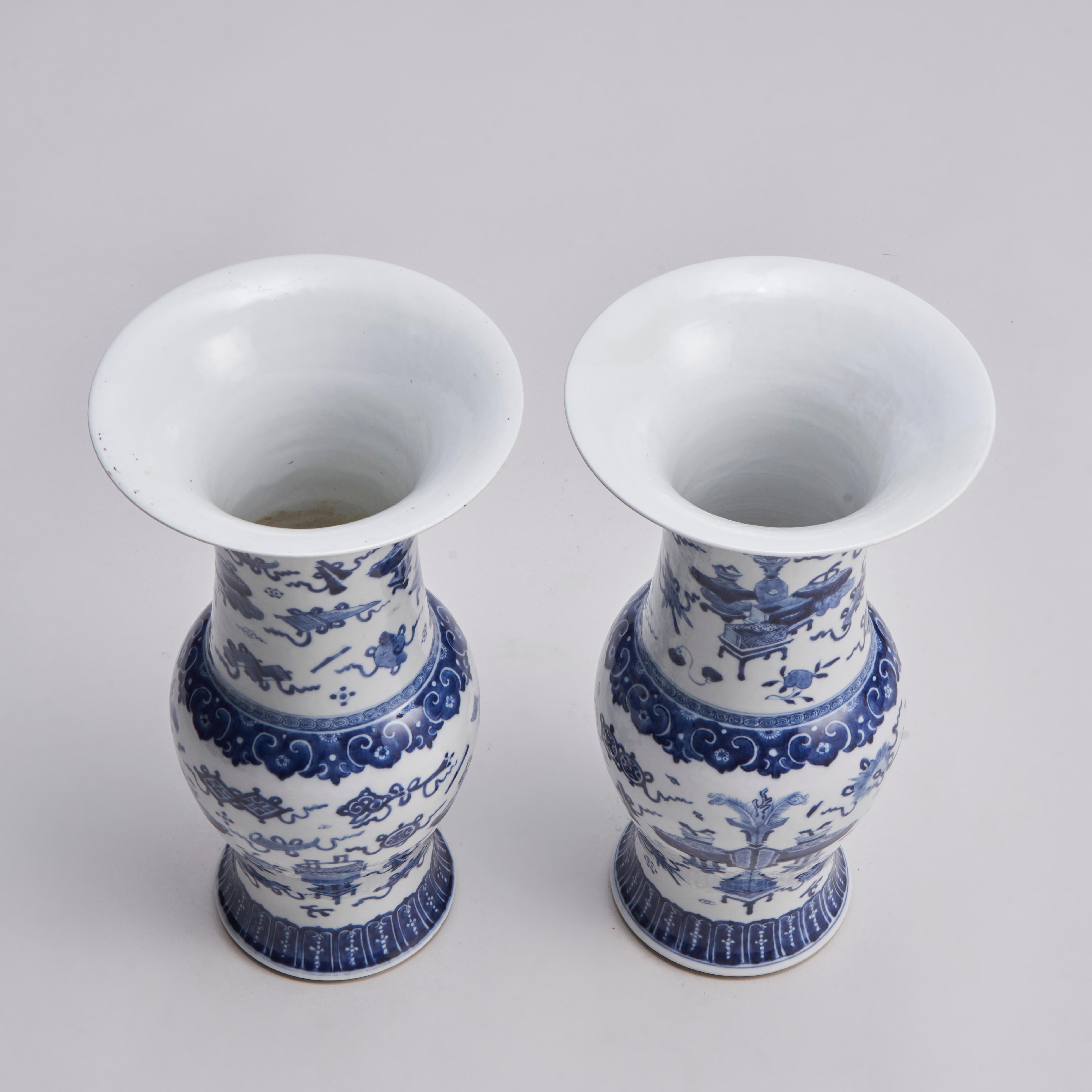 From our collection of antique Chinese porcelain, this pair of 19th century Chinese blue and white Phoenix tail Yen Yen vases (Fengweizun) with fine decoration of precious arcaic bronzes and the auspicious eight treasures on a crisp white