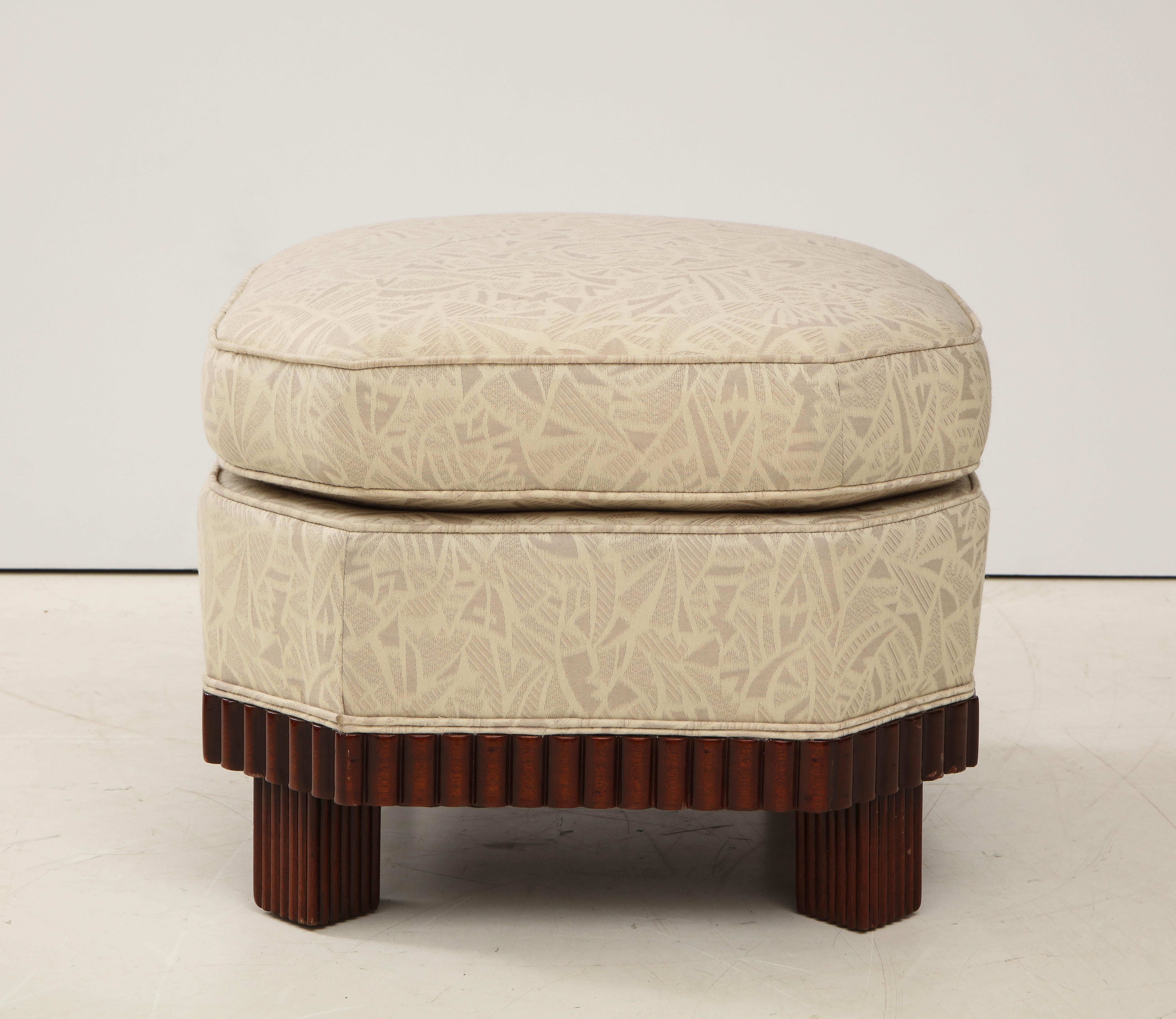 A large pair of French Art Deco footstools or ottomans with octagonal corrugated mahogany bases with block feet surmounted by two tiered upholstered tops with beige tone on tone fabric which may be the original.