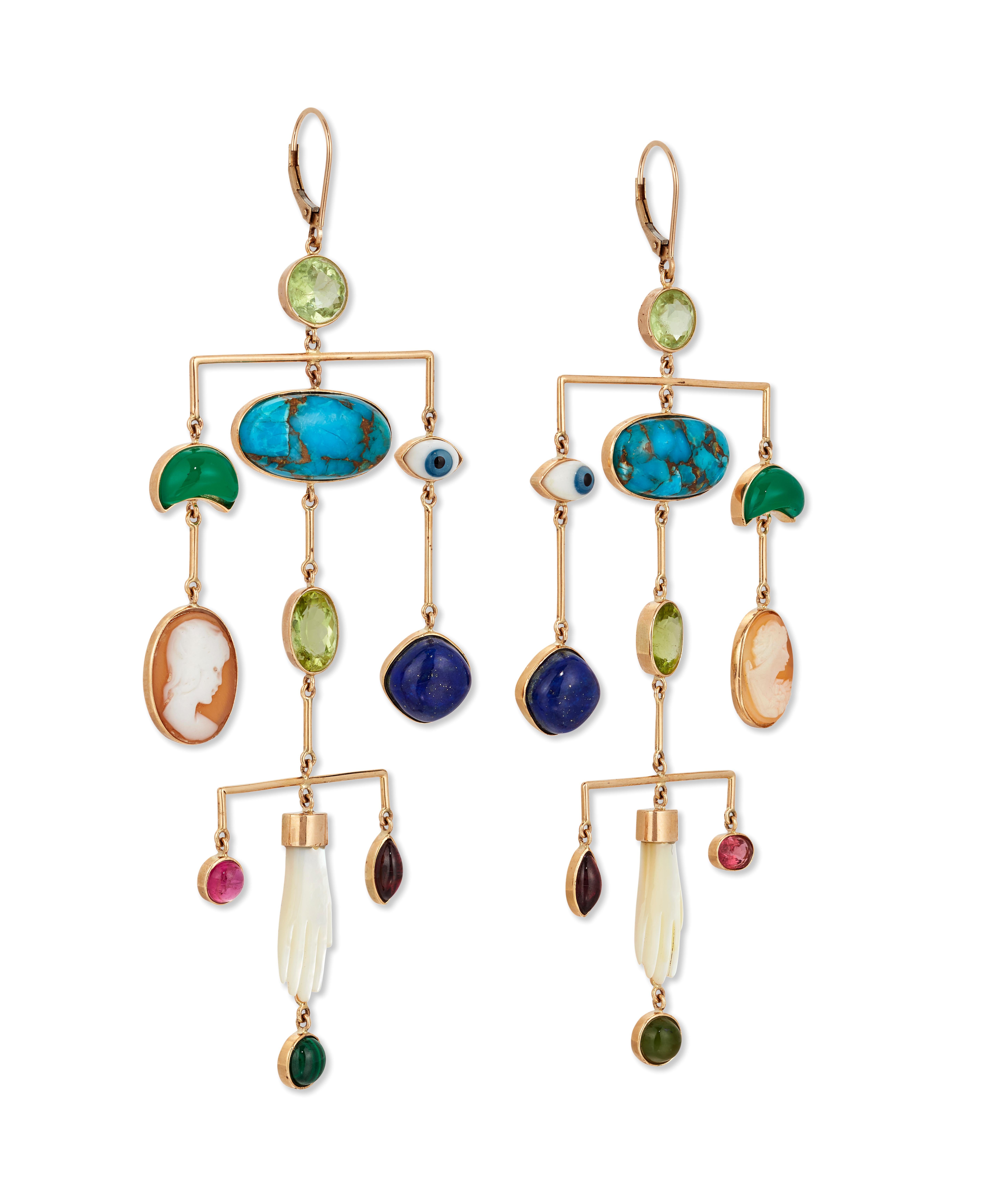 Jeder Anhänger ist mit einer Reihe von antiken Anhängern und facettierten Edelsteinen besetzt, darunter Türkis, Peridot, Chrysopras, Lapis, Granat und geschnitzte Muschelhände.

Hakenbeschläge aus 9-karätigem Gelbgold.