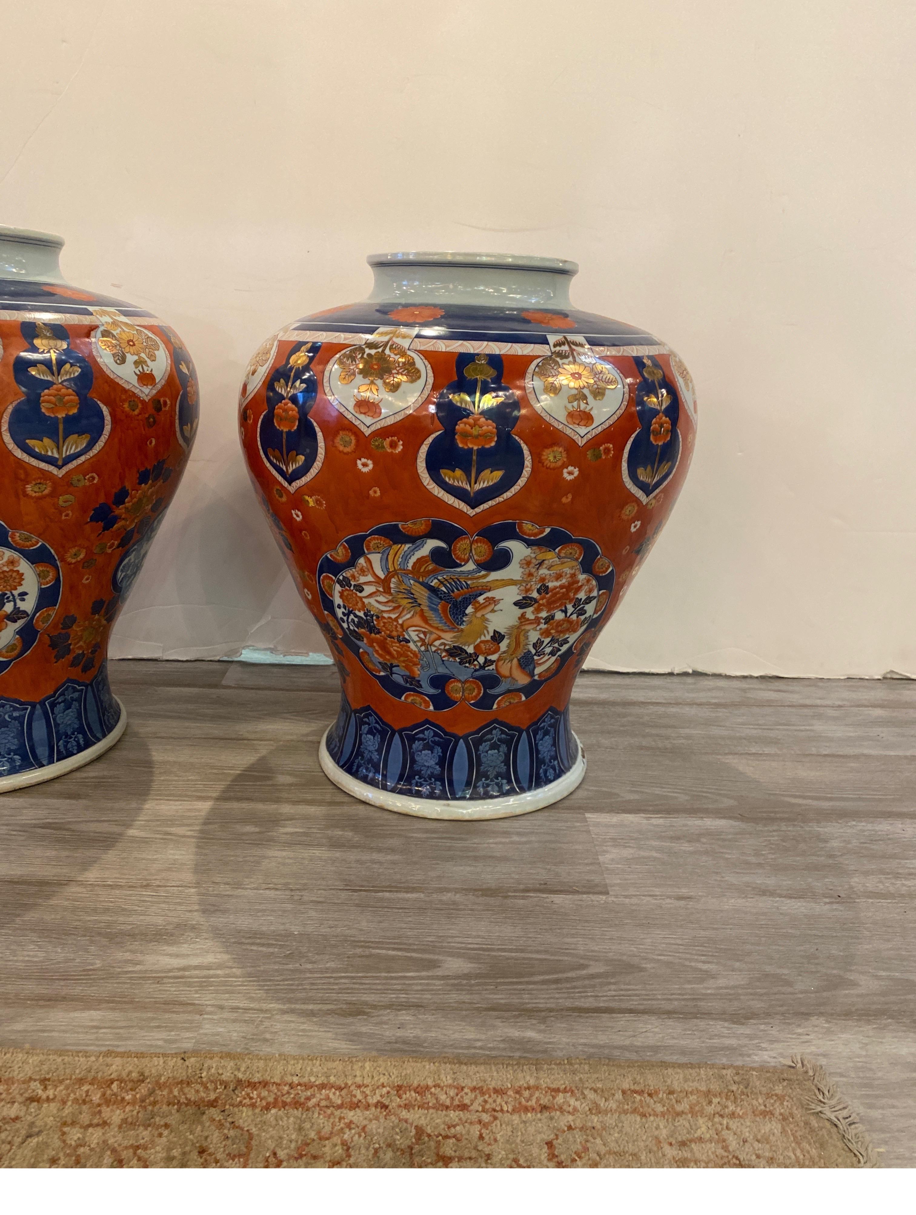 A pair of large Imari pattern porcelain jardinières in classic cobalt blue and iron red with gilt highlights. The white porcelain bulbous form vases all hand painted and an original pair. Beautifully hand painted with phoenix birds, peonies and