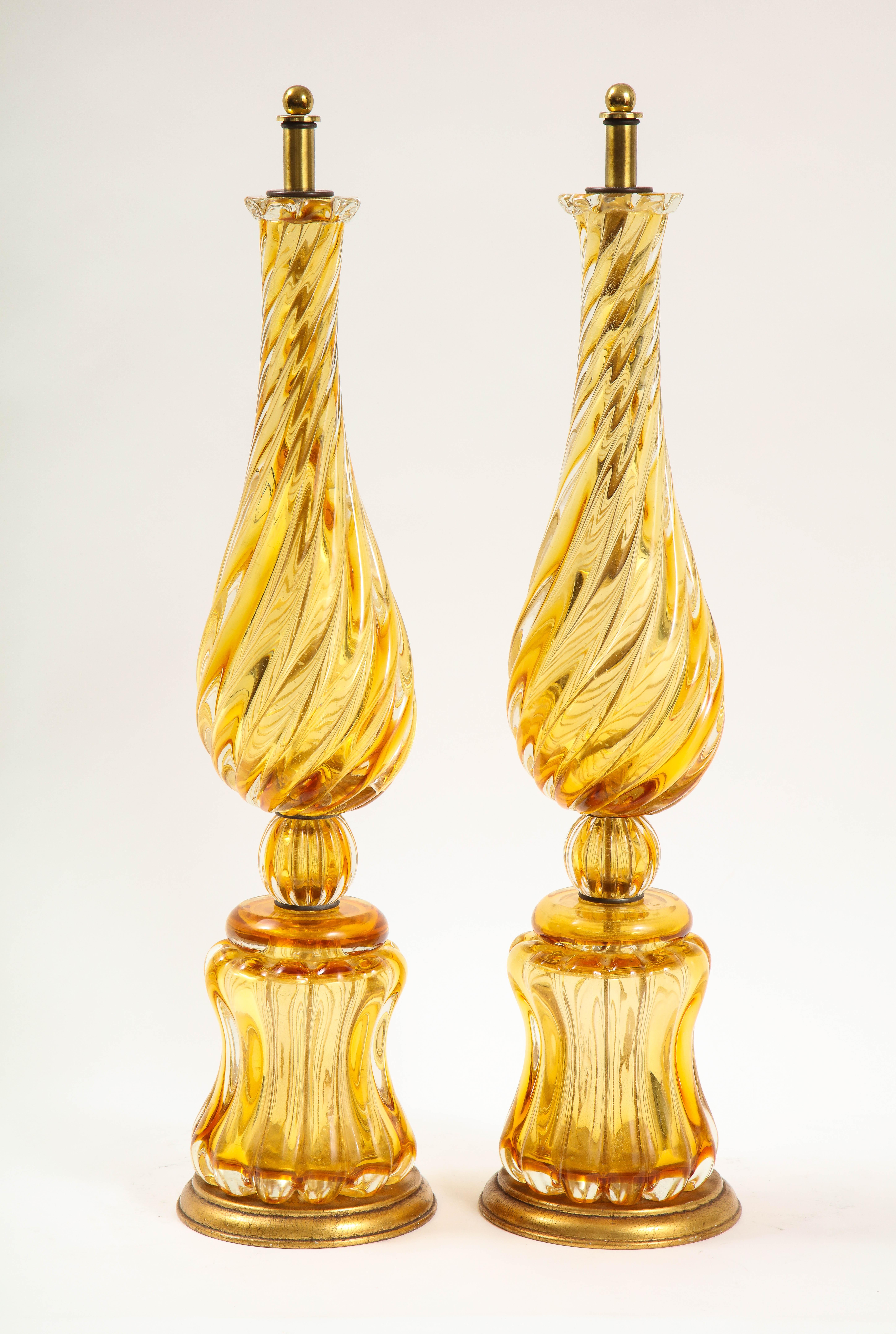 Une grande et très belle paire de cristaux italiens de Murano de couleur ambre, datant du milieu du siècle dernier.  Avec un merveilleux design de cristal tourbillonnant et de belles bases circulaires, cette paire est très inhabituelle et joliment