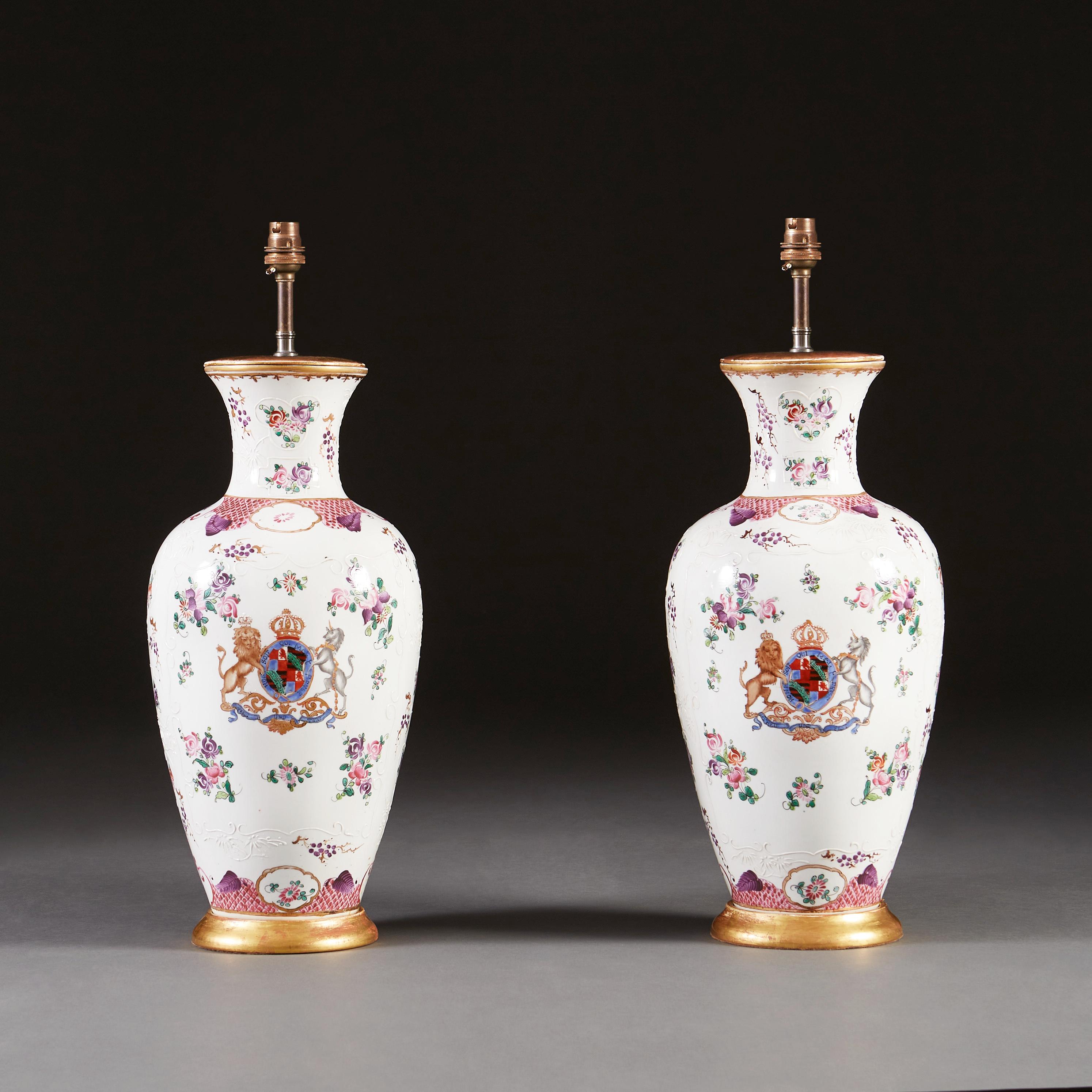A pair of late nineteenth century Samson armorial vases, decorated with floral patterns and a central coat of arms to the front, on a white ground, now mounted as lamps with turned giltwood bases.

Please note: lampshades not