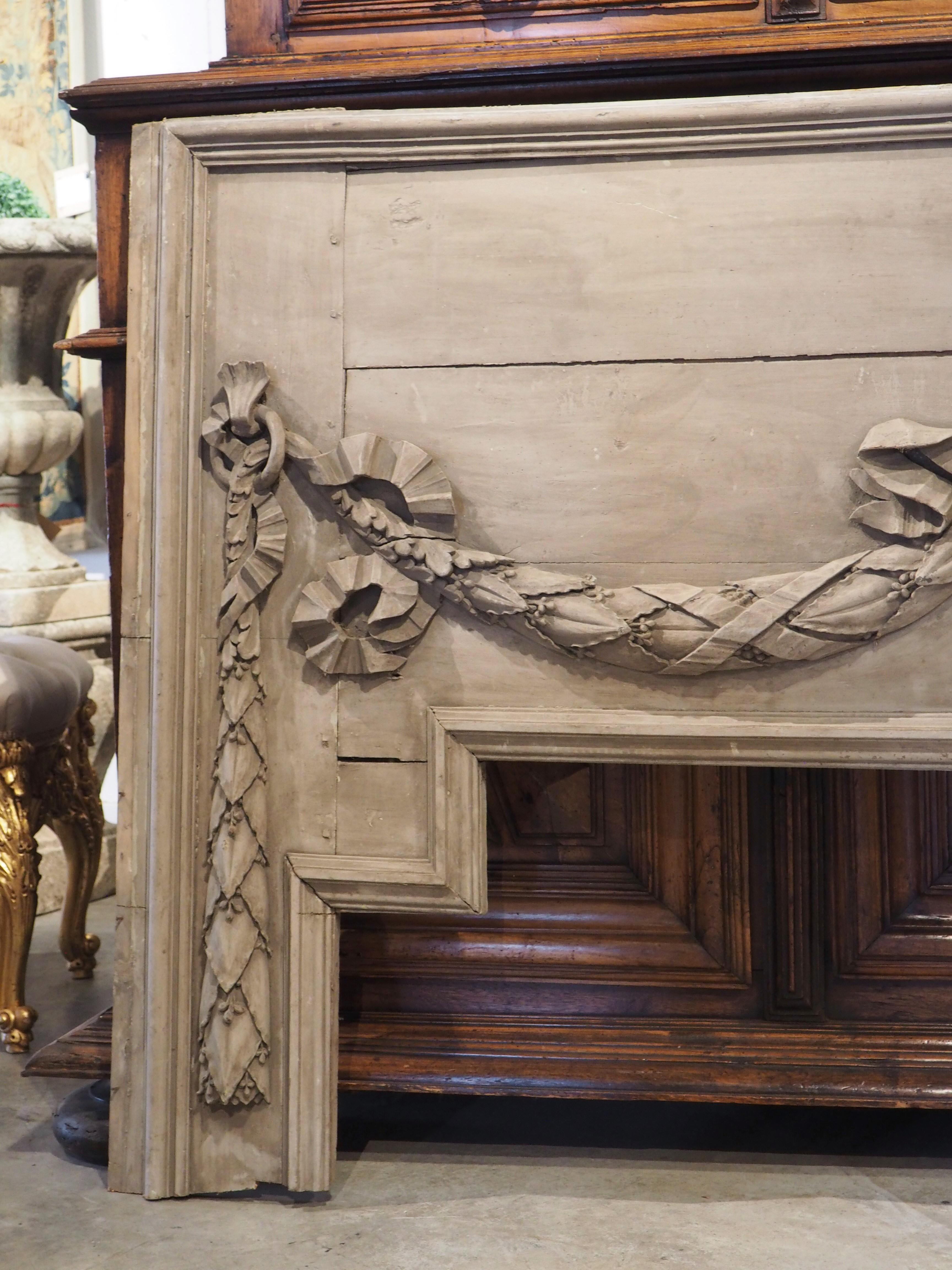 Originally an overdoor from a boiserie room at a French chateau, this large architectural was hand-carved during the Louis XVI period, circa 1790. The overdoor is roughly rectangular, with the exception of the stepped bottom molding, which would
