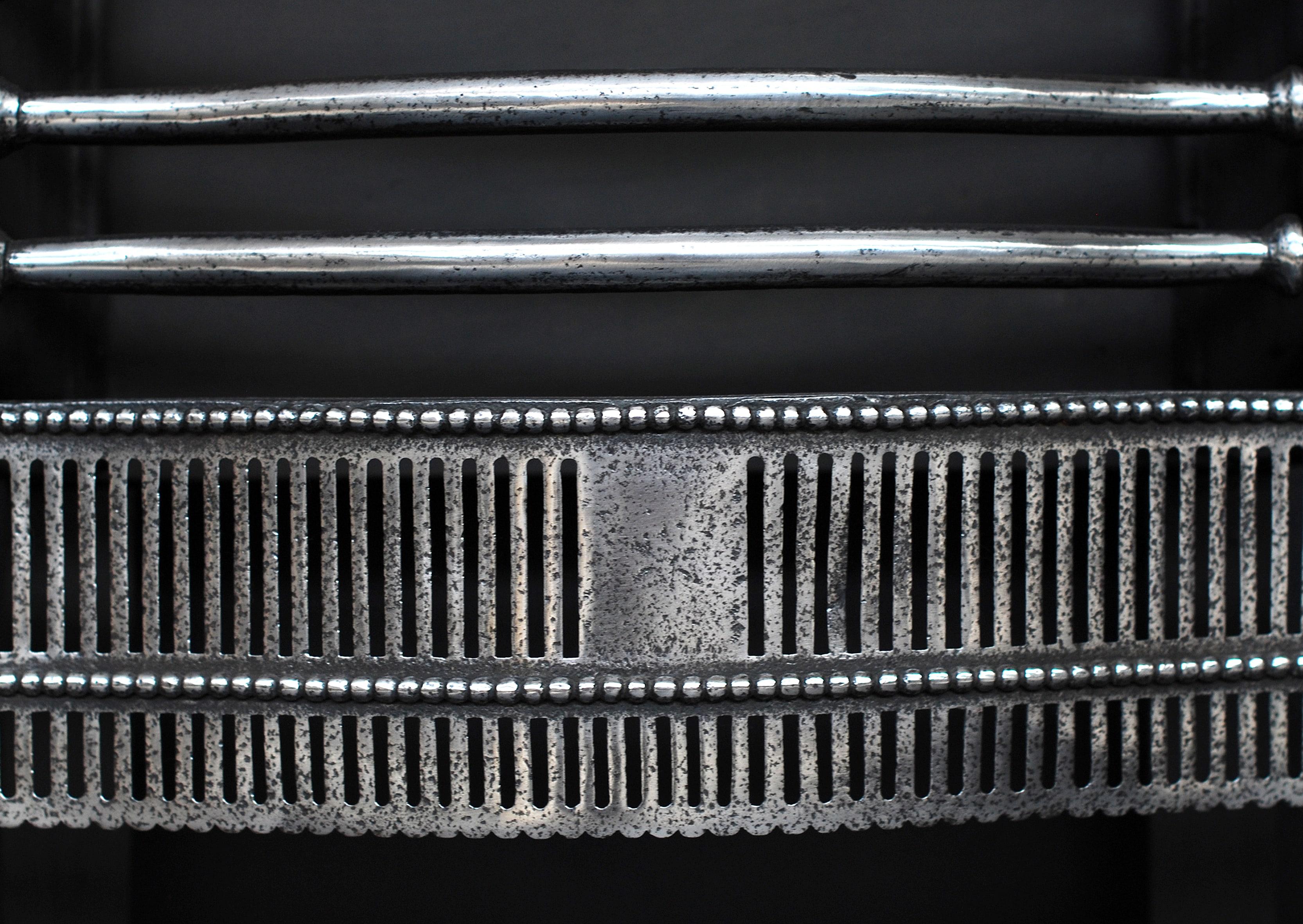 A large polished steel firegrate in the late Georgian style. The pierced, fluted fret with beading above and below, the burning area with shaped front bars, flanked by steel finials. Shaped cast iron back. Late 19th century.

Width At Front:	915 mm 