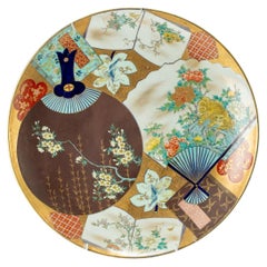 A large porcelain plate finely decorated in polychrome with two fans