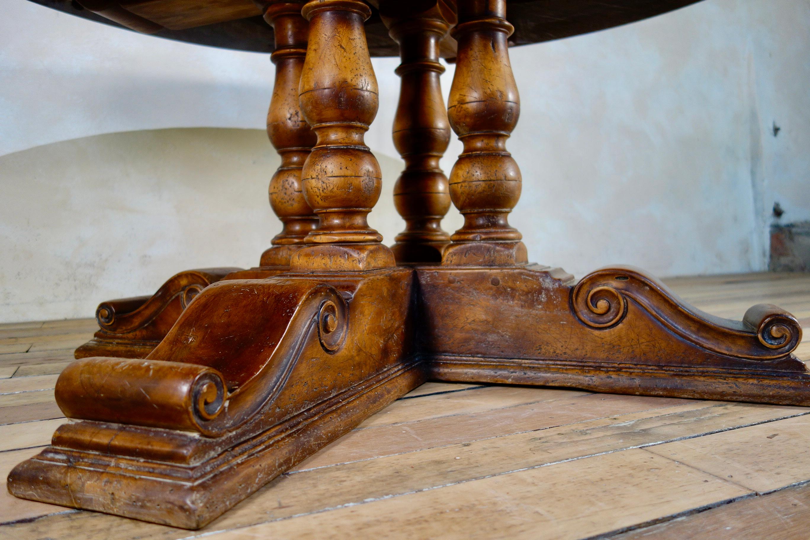 A large early 20th century walnut and oak marquetry center table - raised on a four turned baluster supports sat on a quadripartite sledge base. Demonstrating an extremely thick solid walnut and oak top and base, with a rich and warm patination