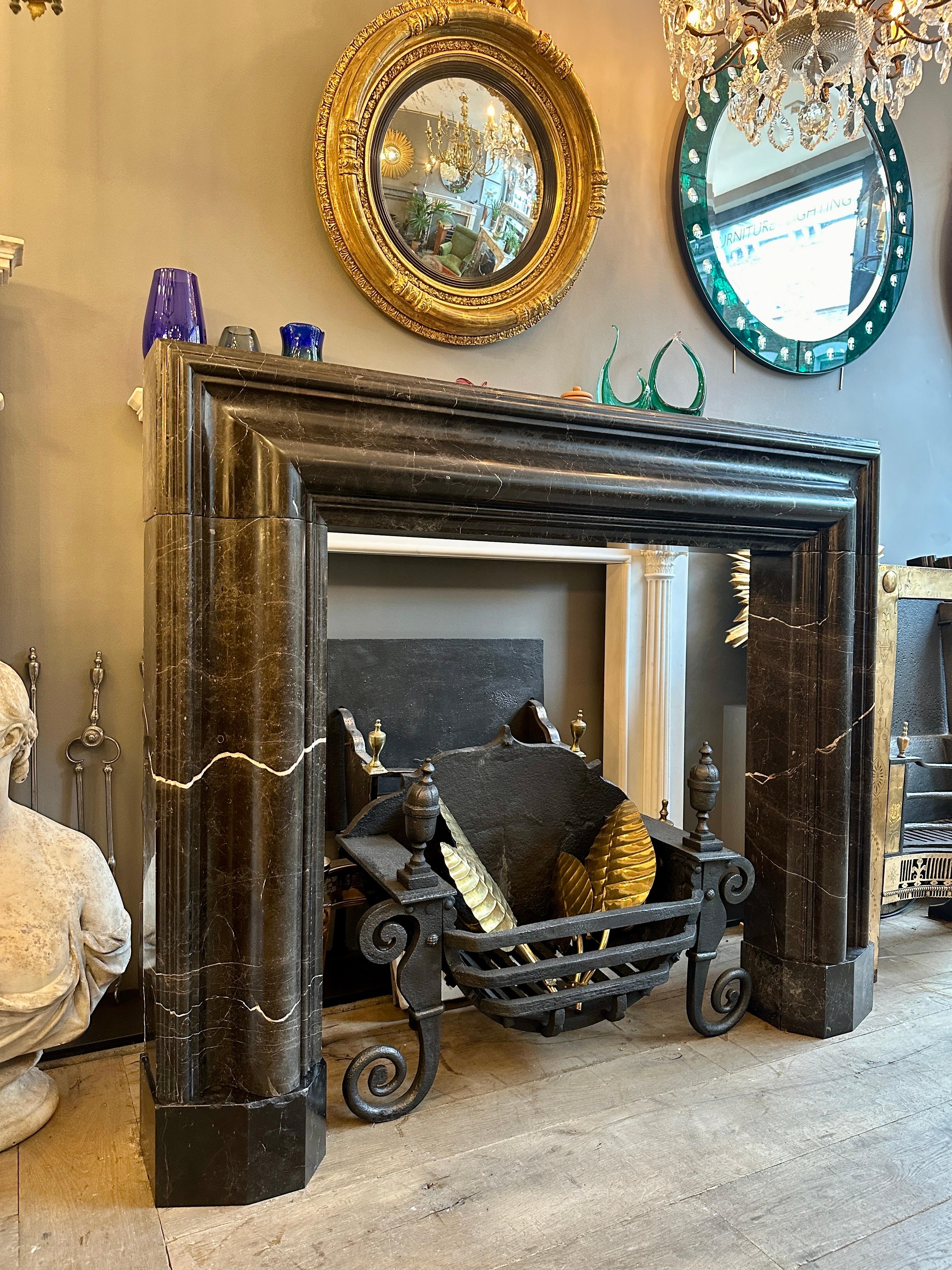 A large substantially sized Bolection frame fireplace in Black marble with white veining. Having a very deep and generous moulding, with stepped and moulded outer edge, shaped foot blocks moulded inner slip. A reclaimed fireplace in good condition,