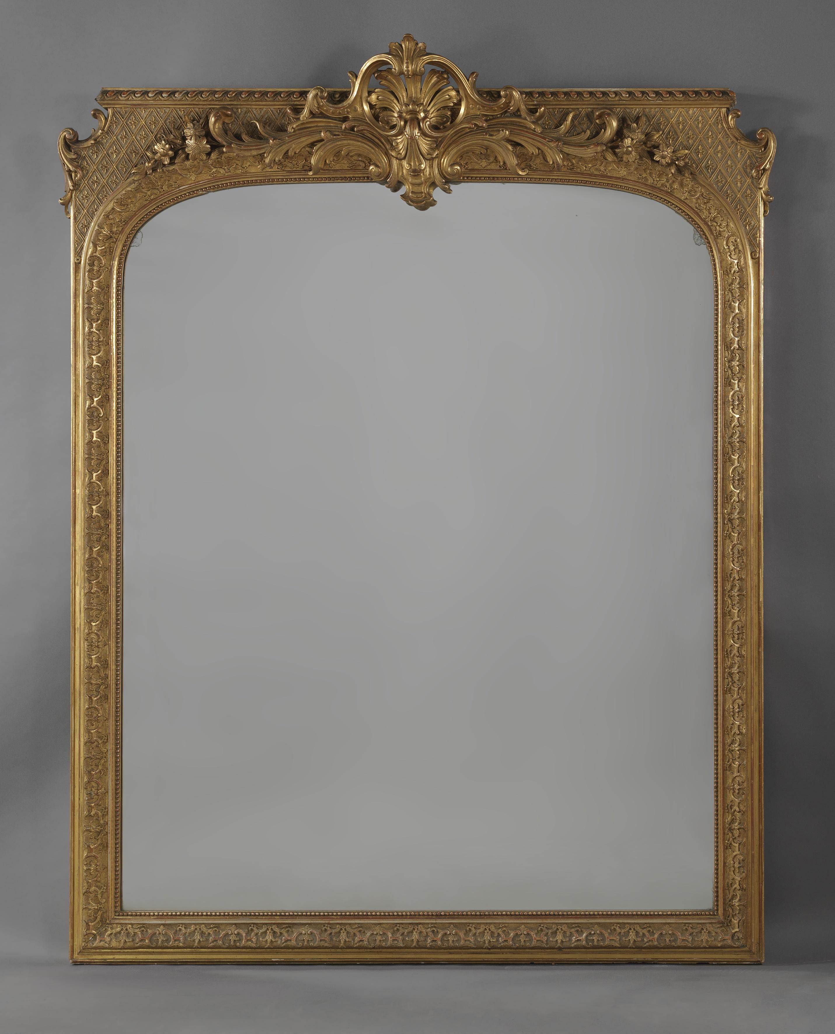 A Large Regence Style Carved Giltwood and Gesso Mirror.

French, Circa 1860. 

This fine mirror is almost 2m in height. The arched mirror plate is framed by carved uprights with beaded decoration and surmounted by an elaborate acanthus cast