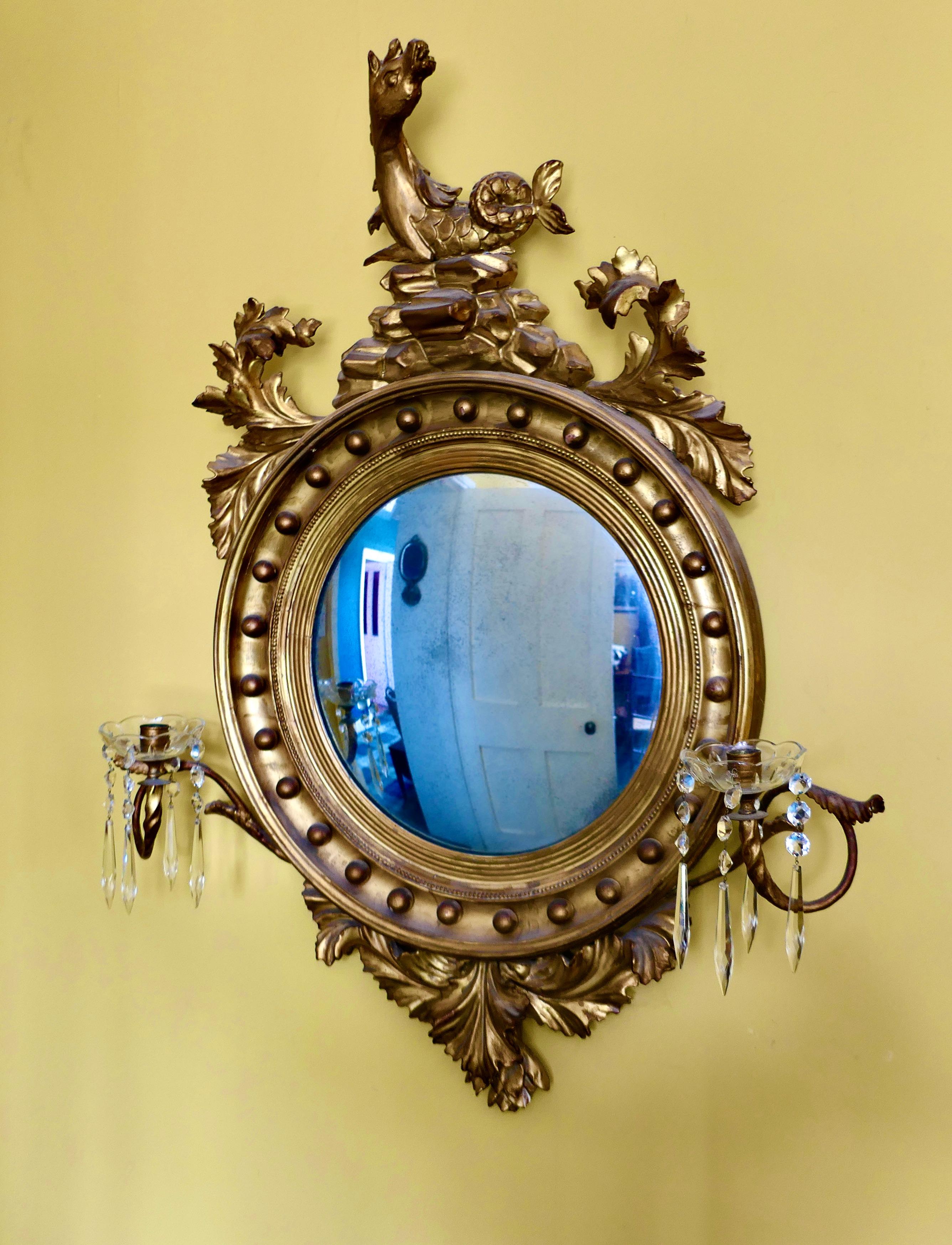 A Large Regency Convex Gilt Girandole Wall Mirror 


This Stunning Mirror has a deep gilt frame decorated with spheres and is finely reeded up to the convex glass, on either side it has a twisted candle branch hung with lustres 
The bottom of the