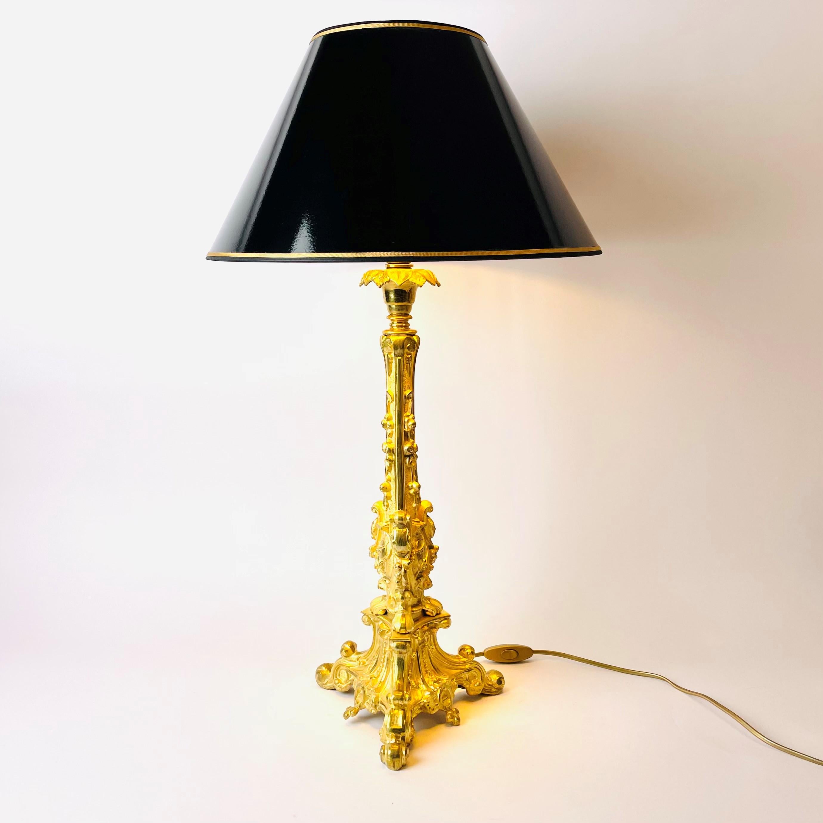 A large and beautiful Rococo Revival table lamp in gilded bronze from mid-19th century. 

Features intricate ornamentation in gilt bronze of typical Rococo floral patterns, flowing upwards from the base of three legs.

The new black lacquer shade is