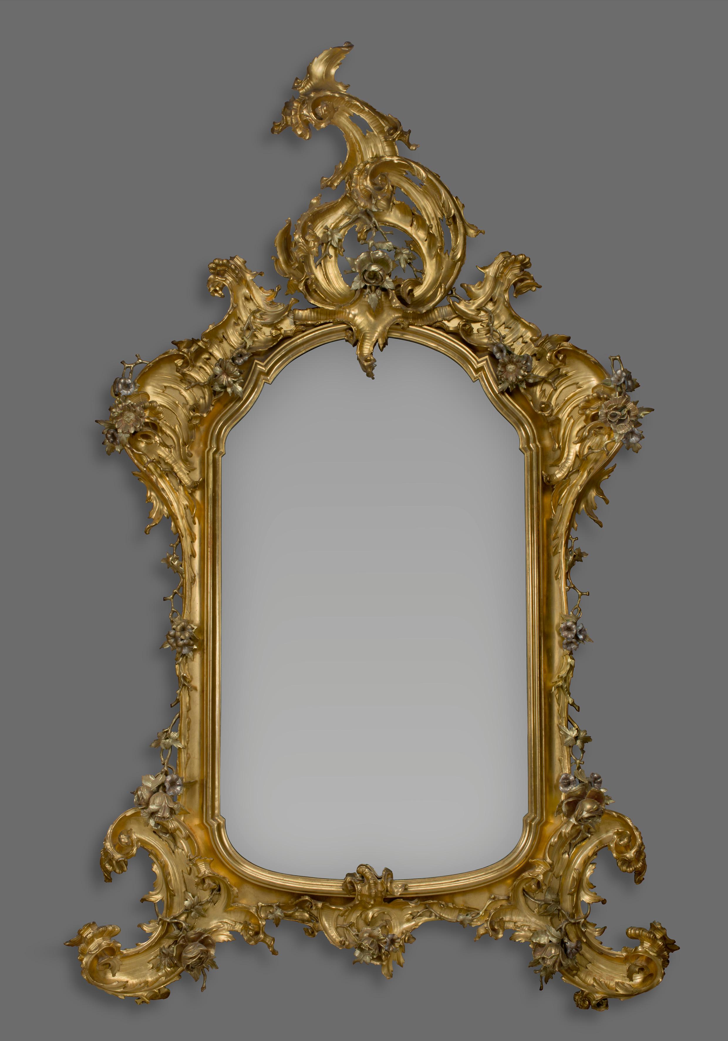 A large Rococo style carved giltwood and silver gilt mirror.

Possibly German, circa 1870. 

The arched mirror plate within a moulded re-entrant inner frame, flanked by an outer frame with exuberant 'C' - scrolls and fronded acanthus to the