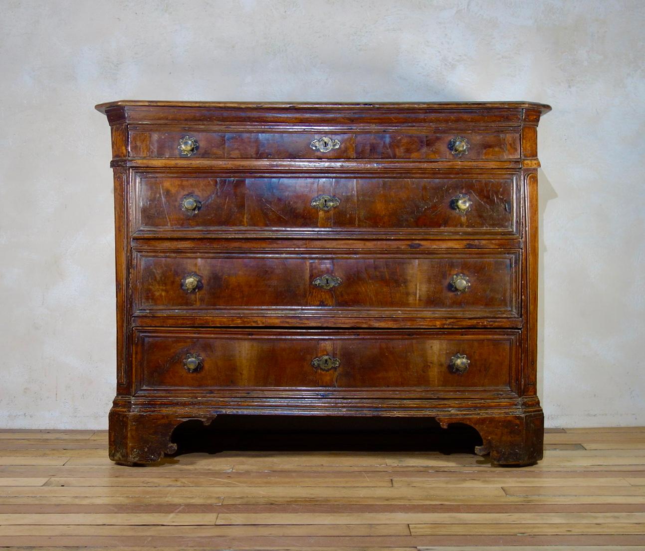 An unusually large 17th century North Italian walnut commode with canted corners. Featuring four long graduated drawers, three of which display molded front panels. 
Each drawer displays a pair of brass Sun handles with matching escutcheon, both of