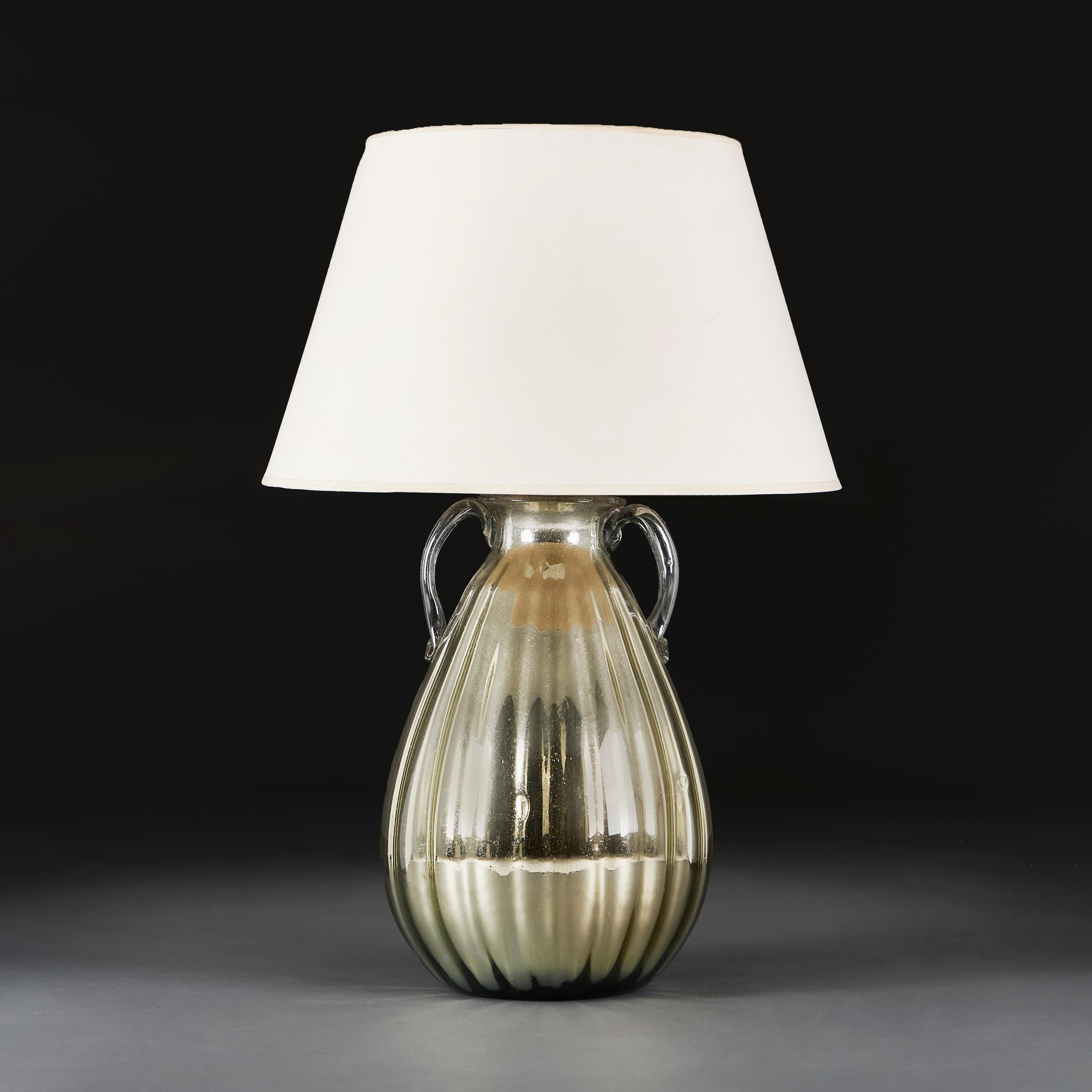 France, circa 1940

An early twentieth century mercury glass vase of large scale, with a gadrooned body, two handles, and a tapering neck.

Height with shade 88 cm. 

Height without shade 52 cm. 

Diameter 34 cm. 

Please note:

Lampshade not