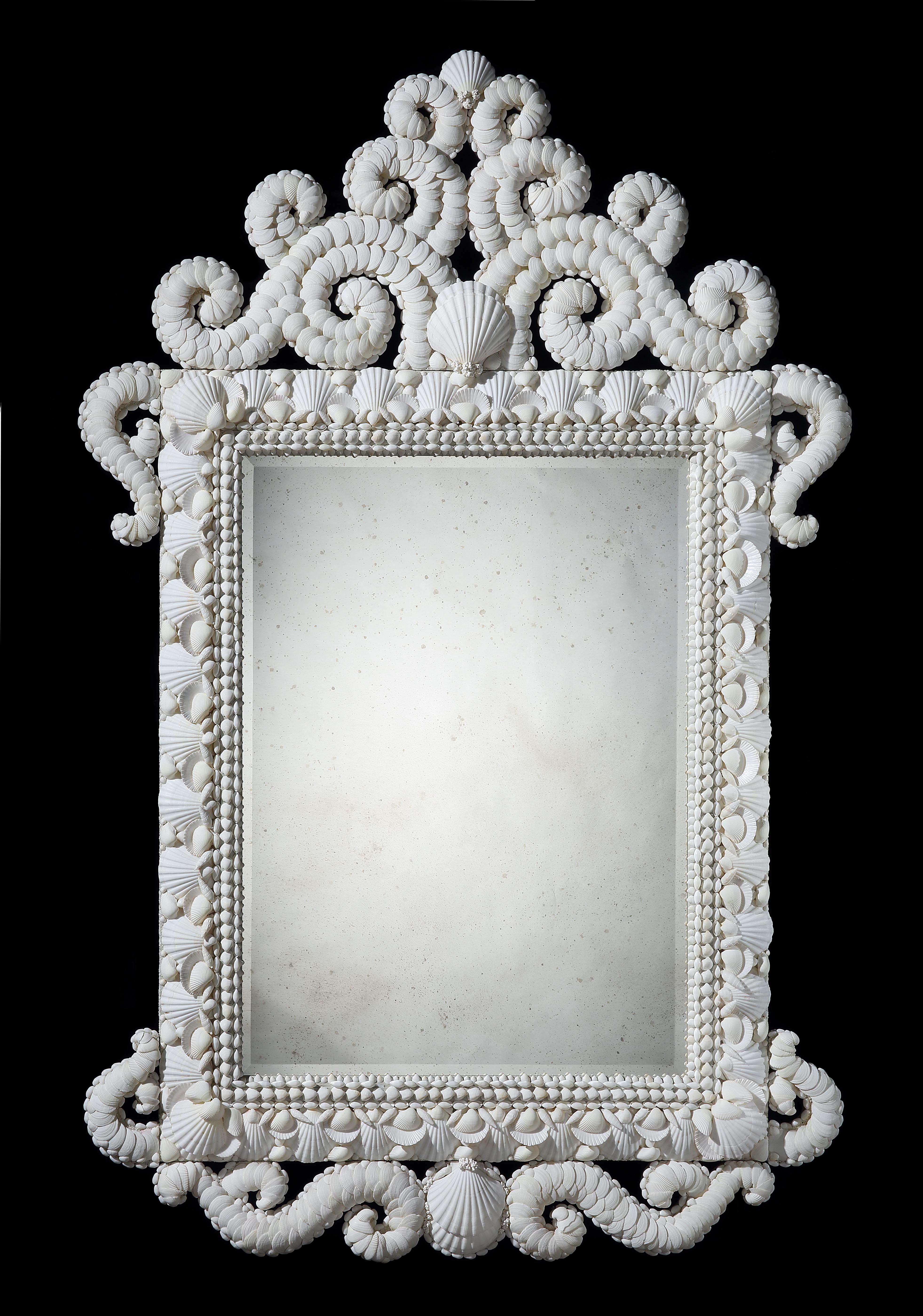 A very fine white shell mirror of large scale with cresting and scrolled sides and apron. The mirror plate bevelled and hand distressed. 

By Tess Morley.
