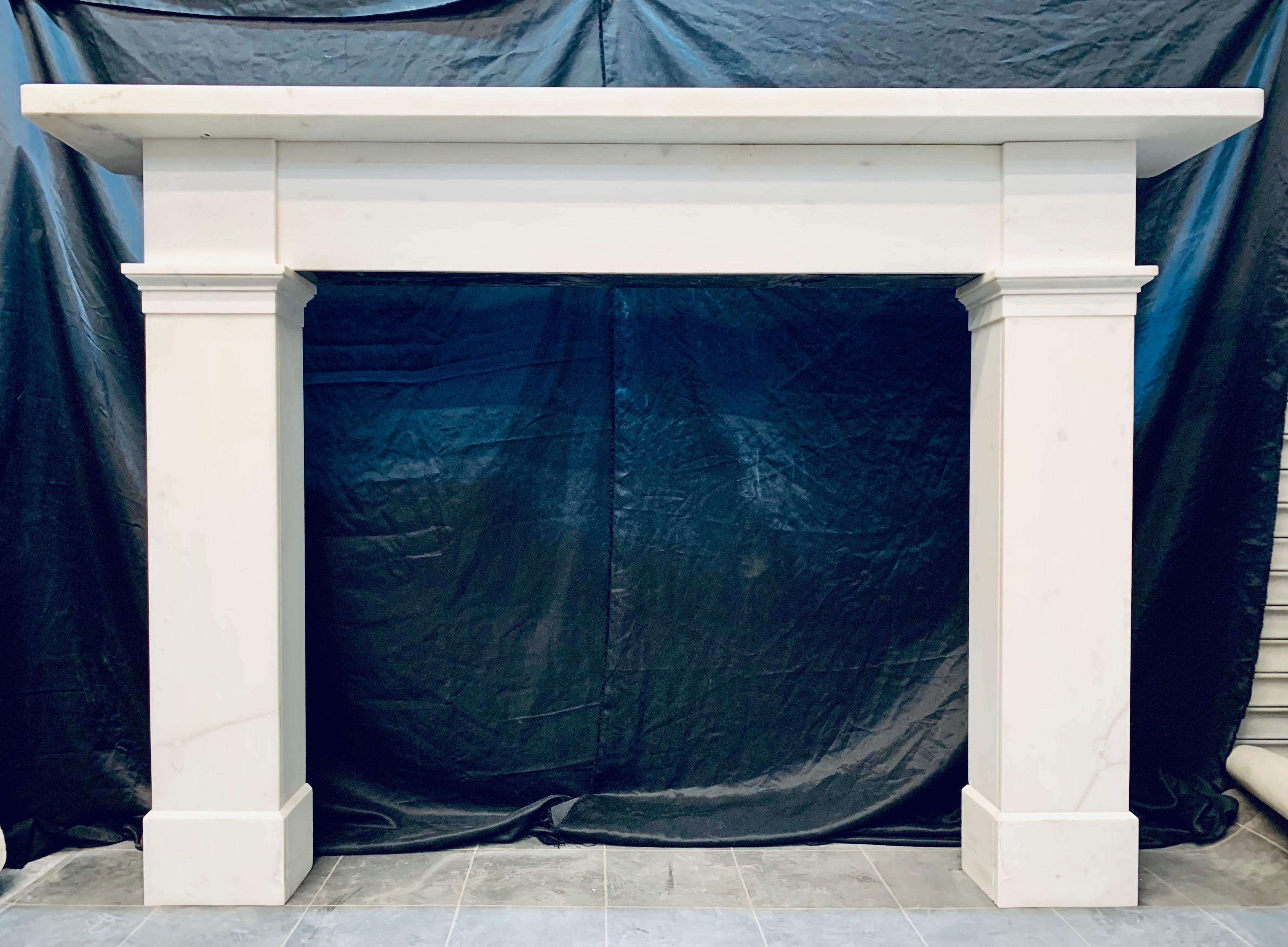 A large Scottish late Georgian 19th century statuary marble fireplace surround originally from Edinburgh’s New Town. 

A generous square edged top shelf, sits above an unadorned central frieze, flanked by plain capitols, below, a moulded and