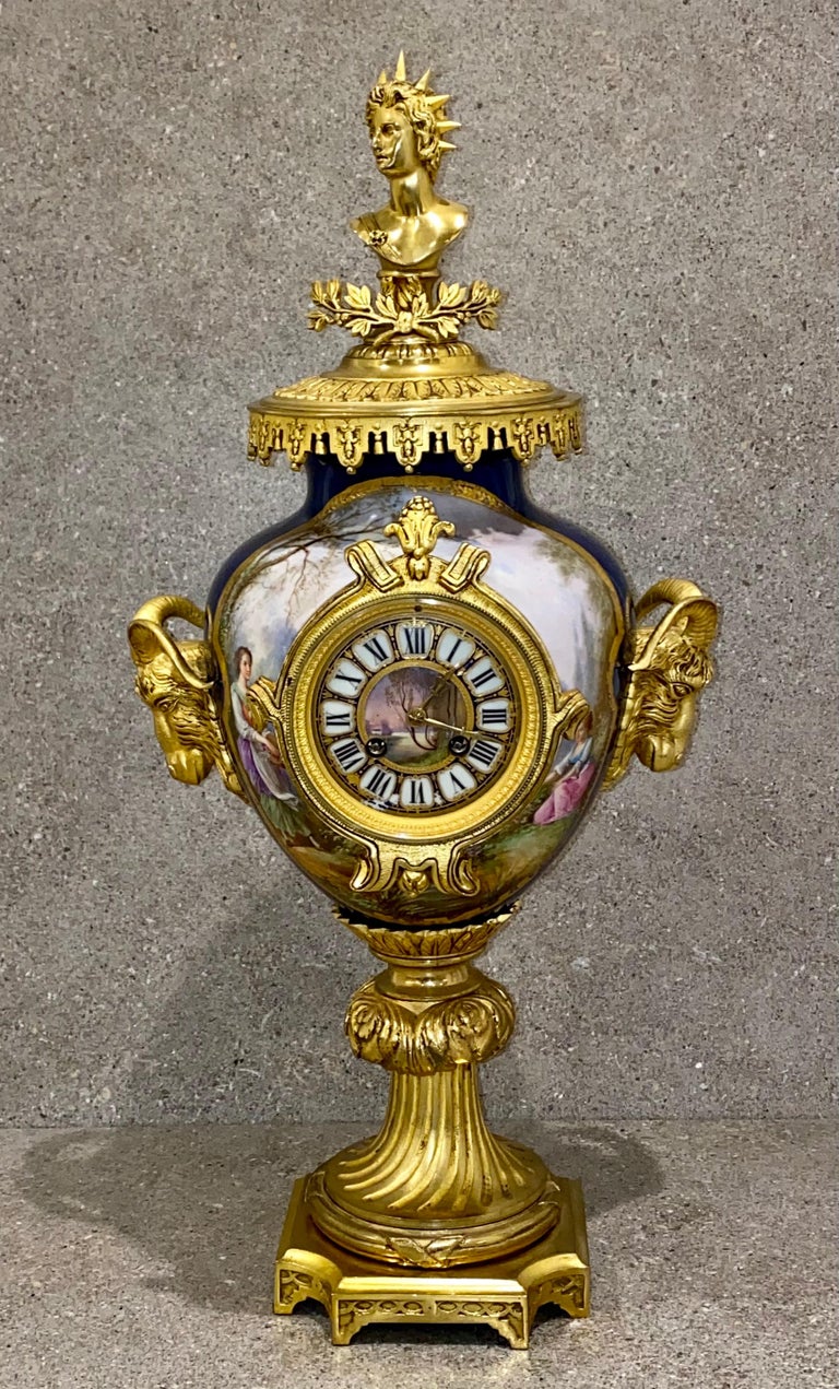 This superb quality Sevres style porcelain and ormolu clock garniture consists of three vases, one of which has been mounted with an exquisite jewelled clock dial. This set comprises a central vase, which has been fitted with a clock, and a pair of