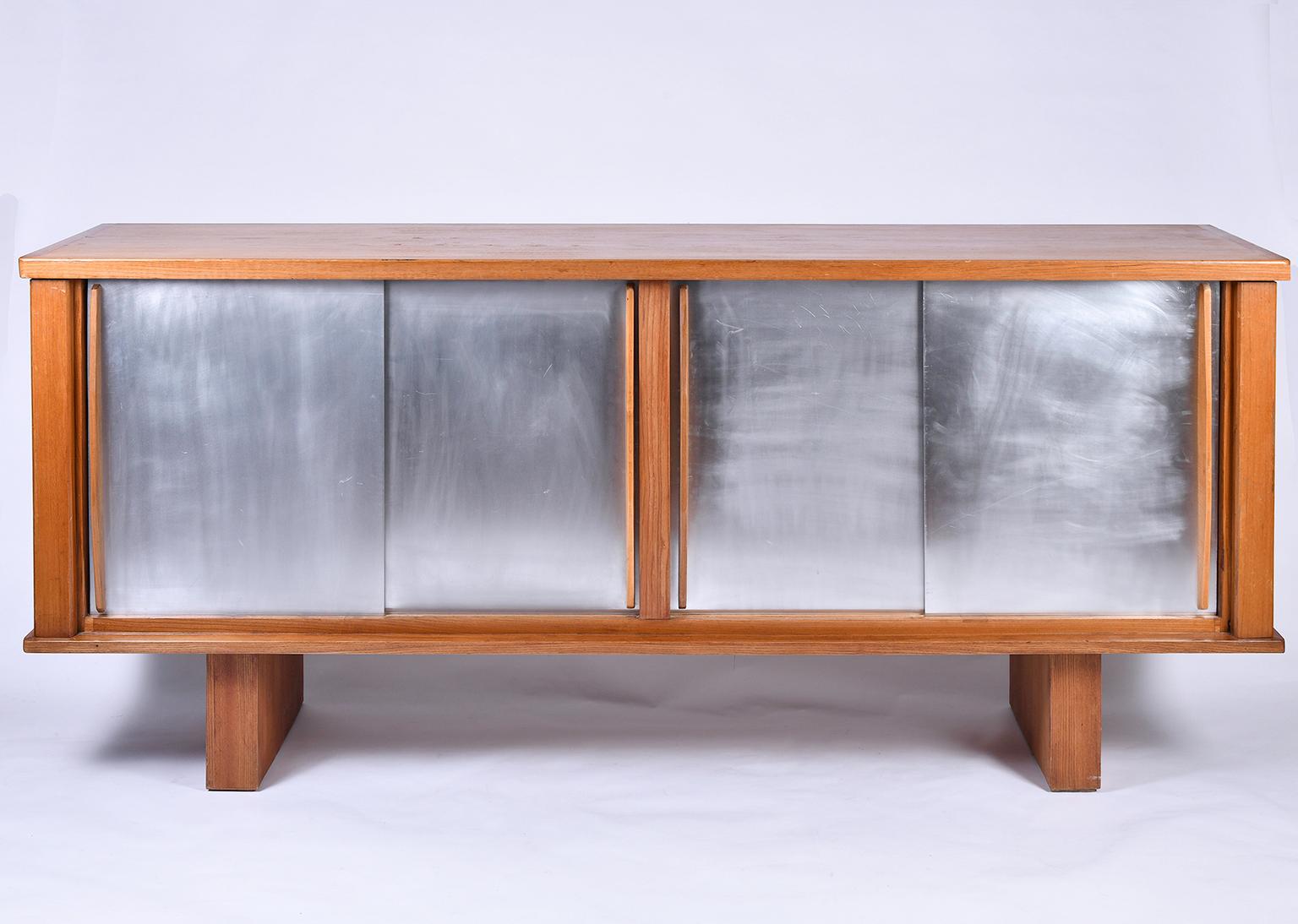 A large ash and aluminium sideboard in the manner of Charlotte Perriand, the four sliding door with shaped handles revealing adjustable shelves
France, circa 1950.
 